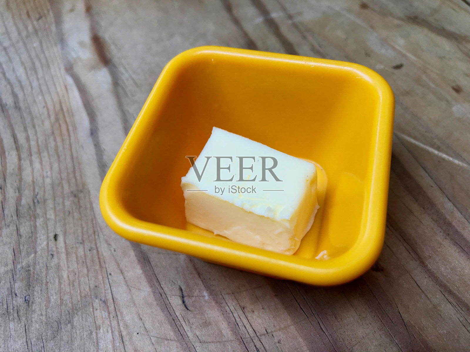 黄油片在黄色塑料杯准备使用。照片摄影图片