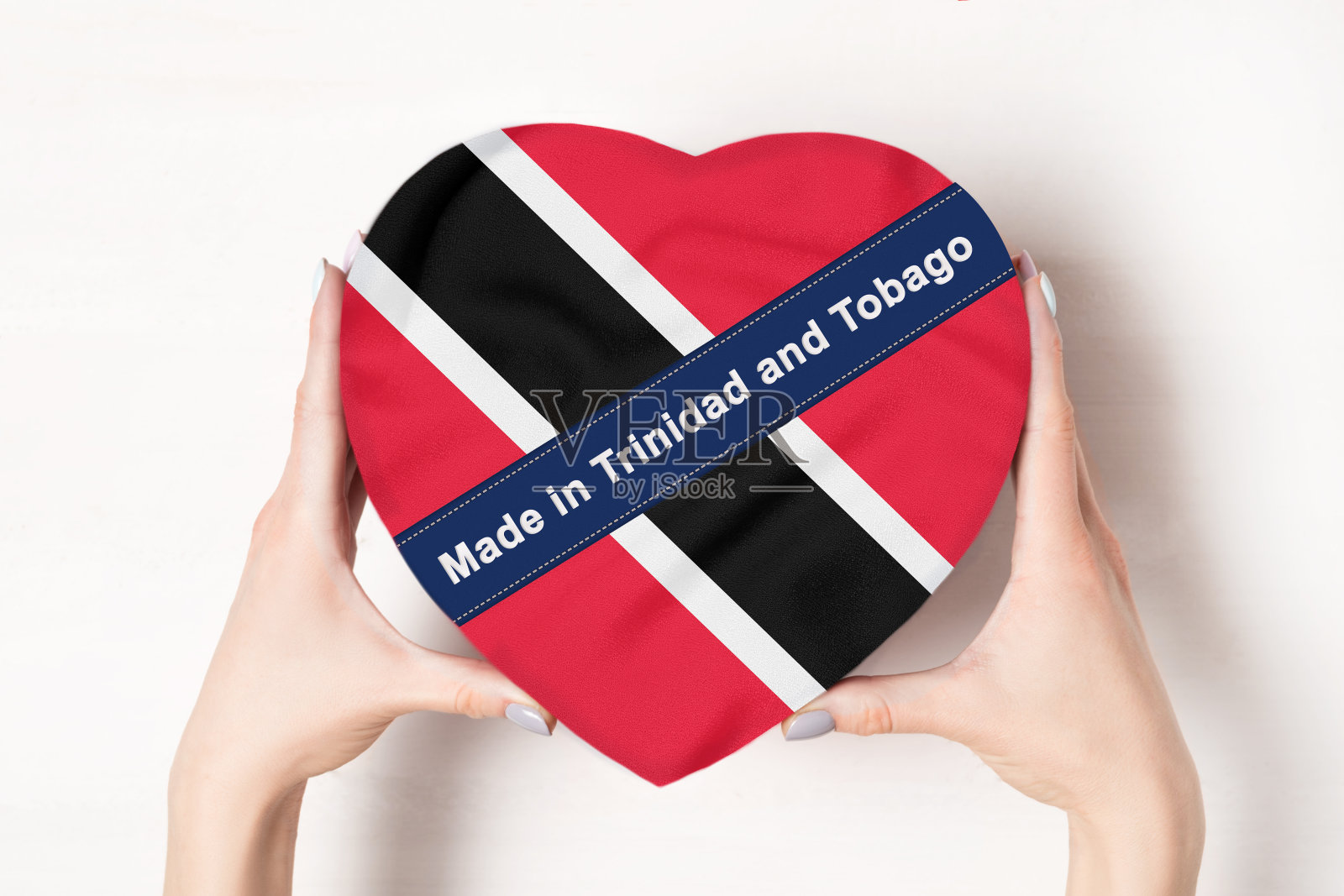 铭文:特立尼达和多巴哥国旗。女人的手拿着一个心形的盒子。白色背景。照片摄影图片
