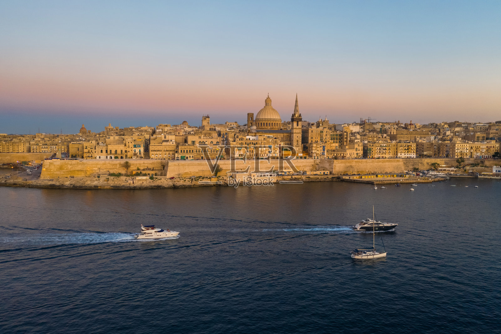 瓦莱塔的城市。鸟瞰图瓦莱塔天际线在晚上,日落。海上的小船照片摄影图片