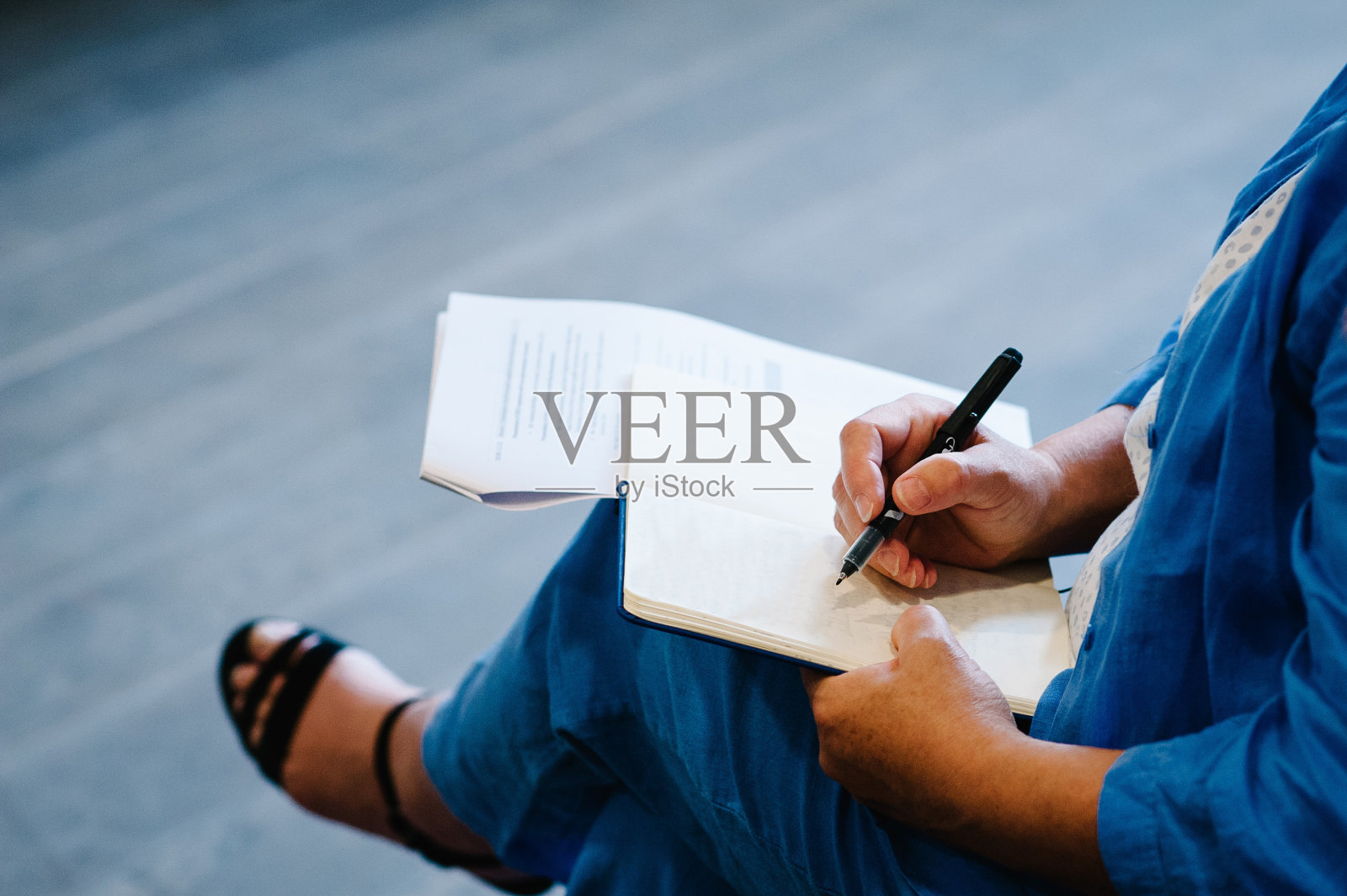 一个女人在一张白纸上写字。文本。一个西装革履的商人的双手在膝盖上签署或书写文件。关闭了。照片摄影图片