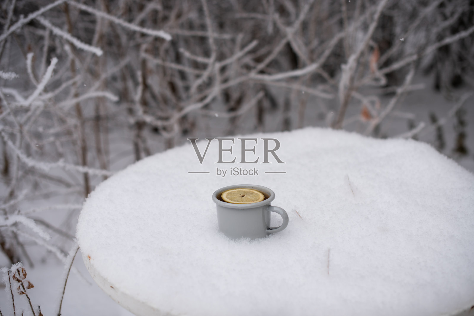 在冬天森林里的一张桌子上,在雪地里喝着一杯茶照片摄影图片