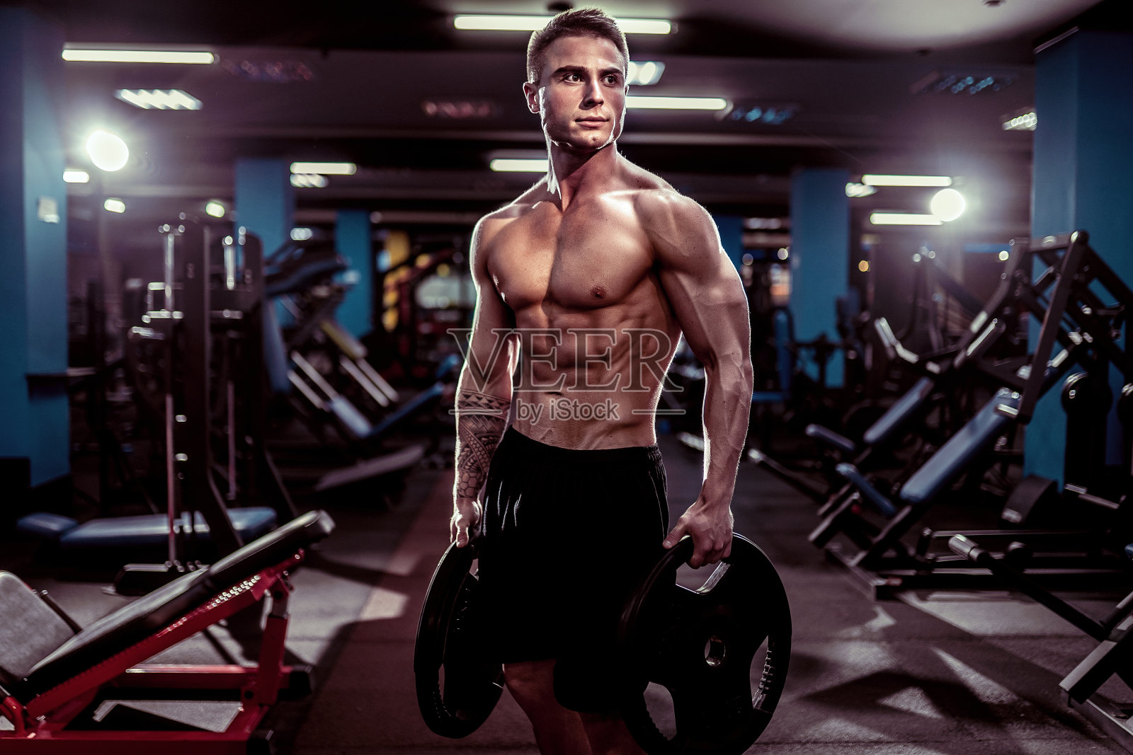 在健身房里摆姿势的白人英俊的健身模特。男人在节食收缩肌肉和六块腹肌照片摄影图片