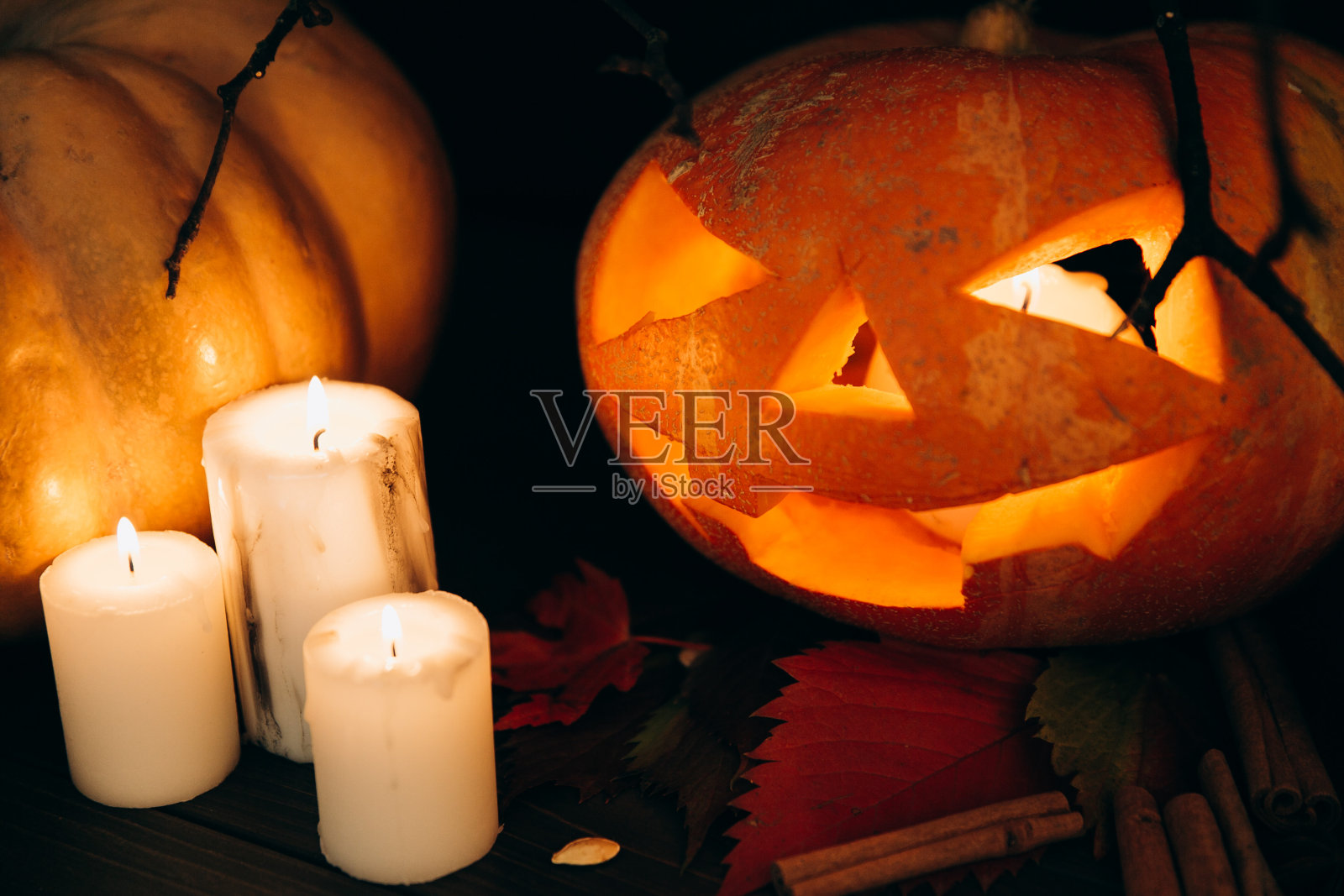 白色的蜡烛站在可怕的万圣节南瓜前肉桂照片摄影图片