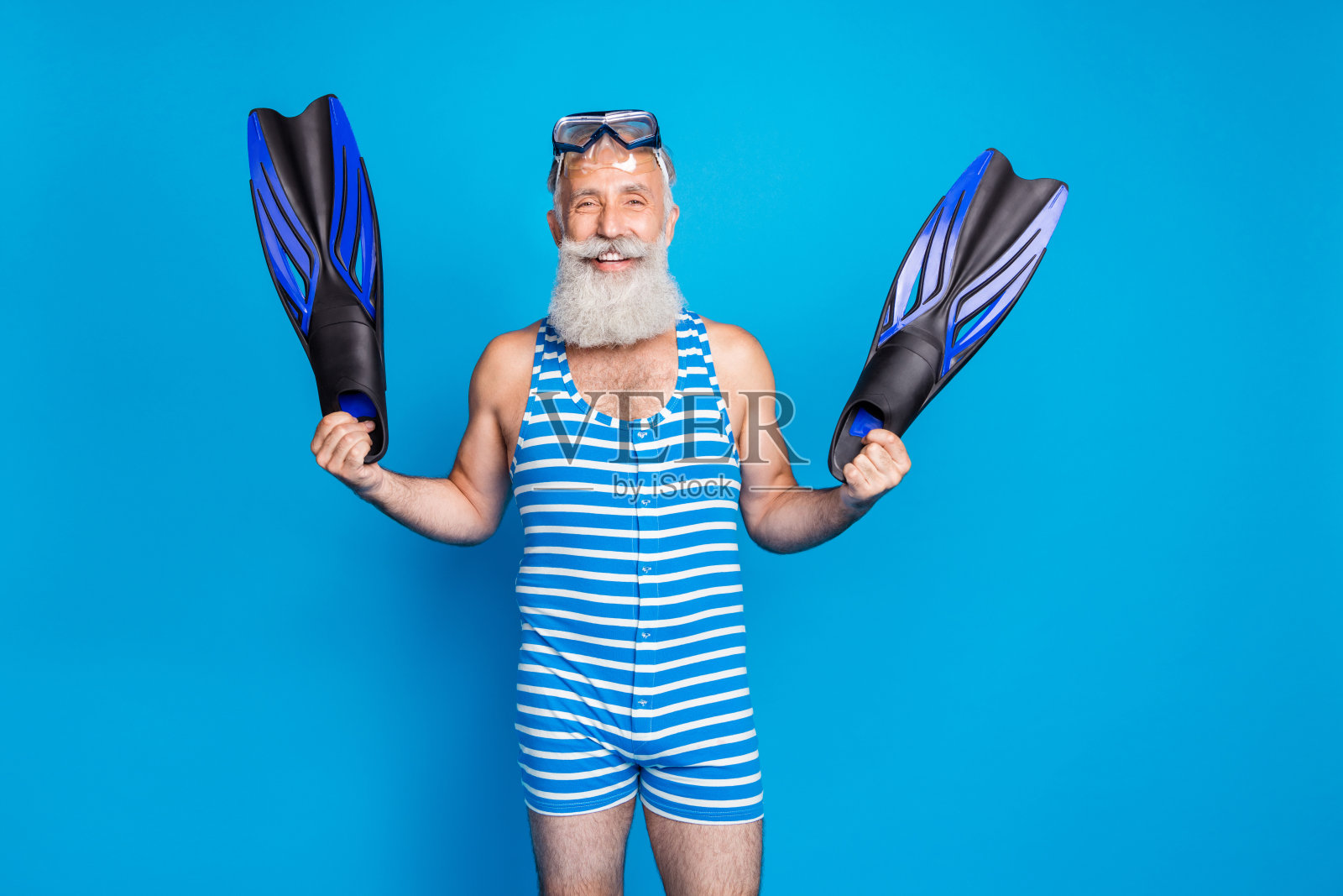 快乐的退休水手的肖像拿着鳍微笑着穿着条纹服装孤立在蓝色的背景照片摄影图片