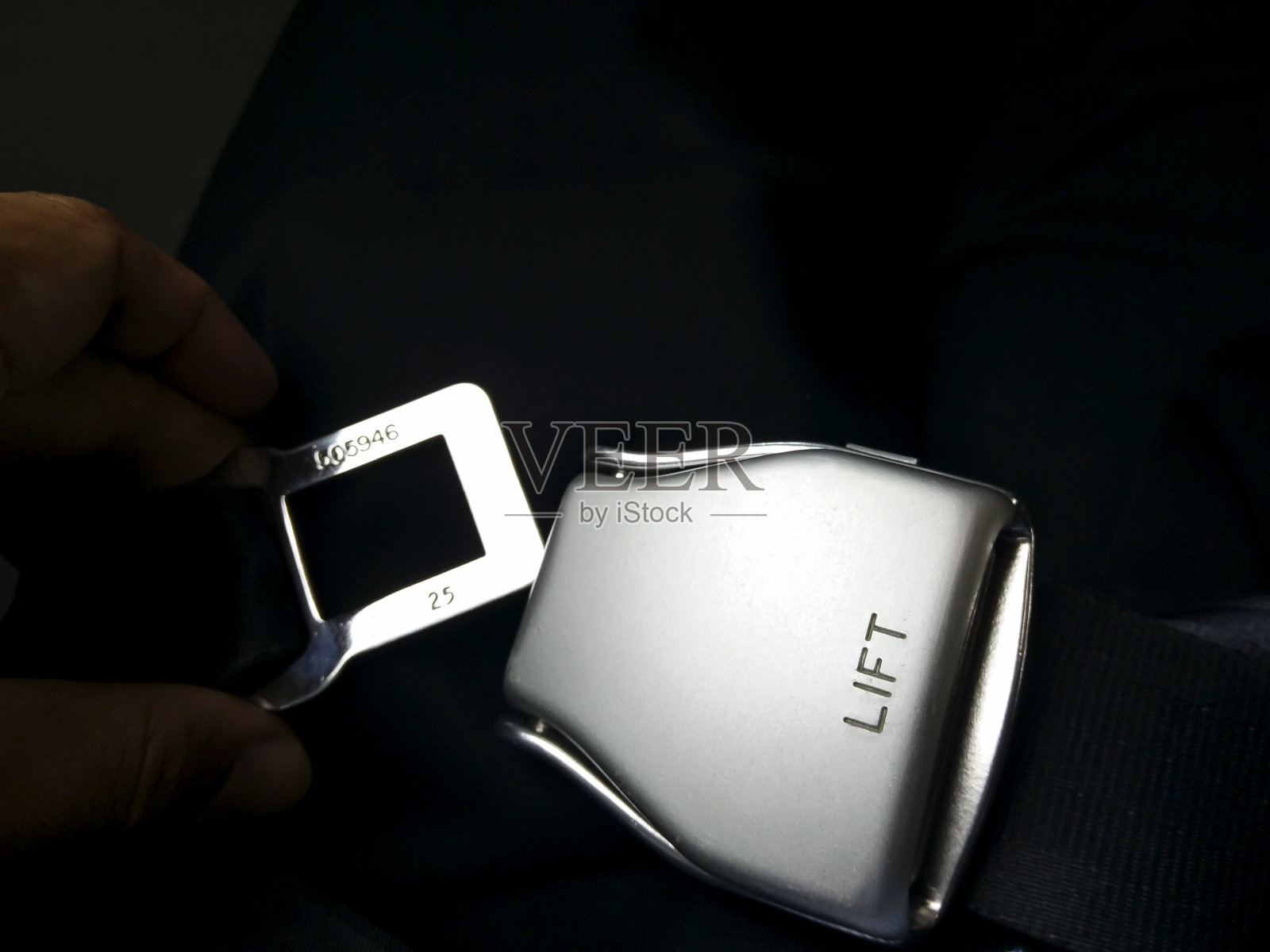 乘客的双手正在系好飞机上的安全带,为飞行做准备。照片摄影图片