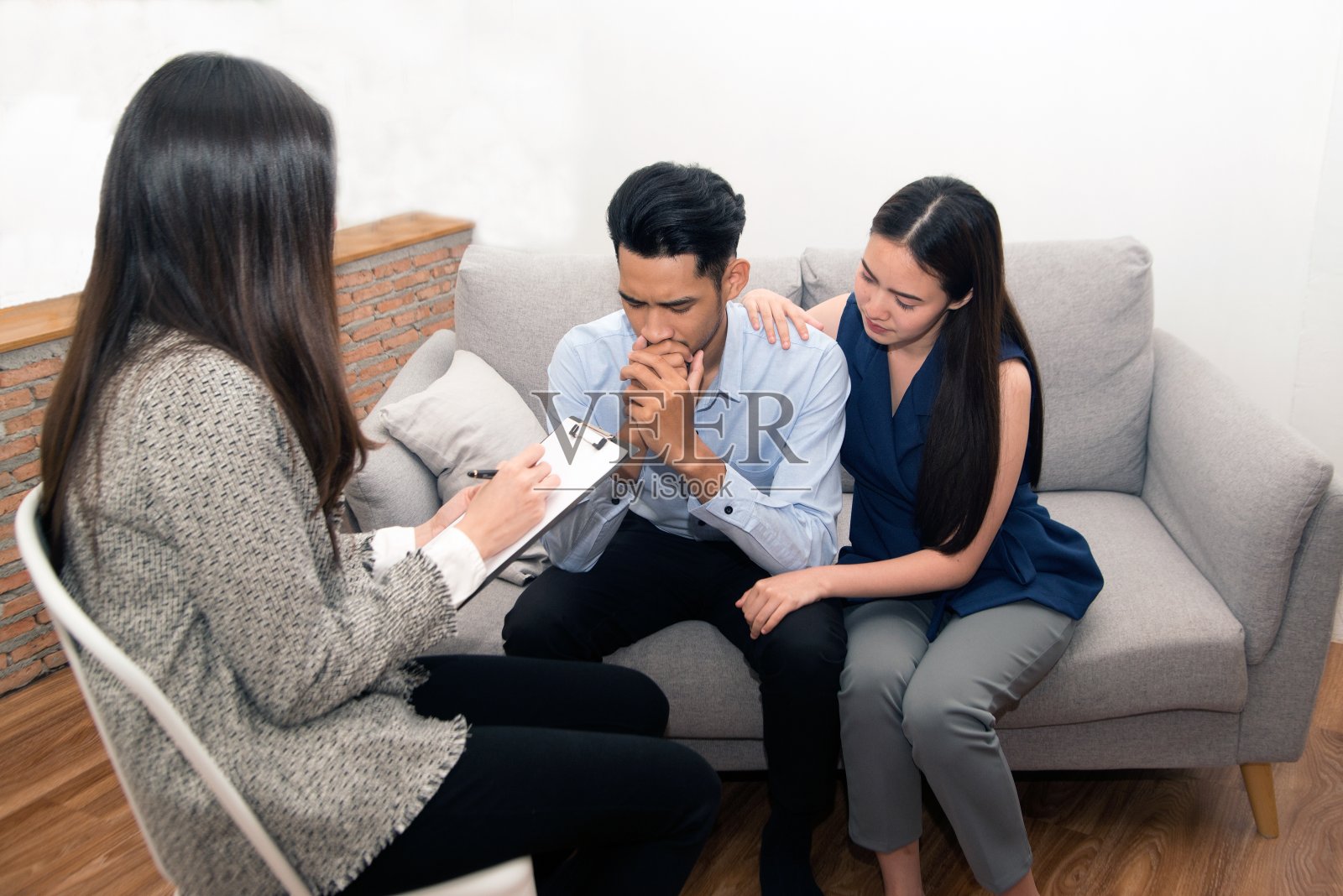 一对亚洲夫妇和心理学家坐在沙发上。照片摄影图片