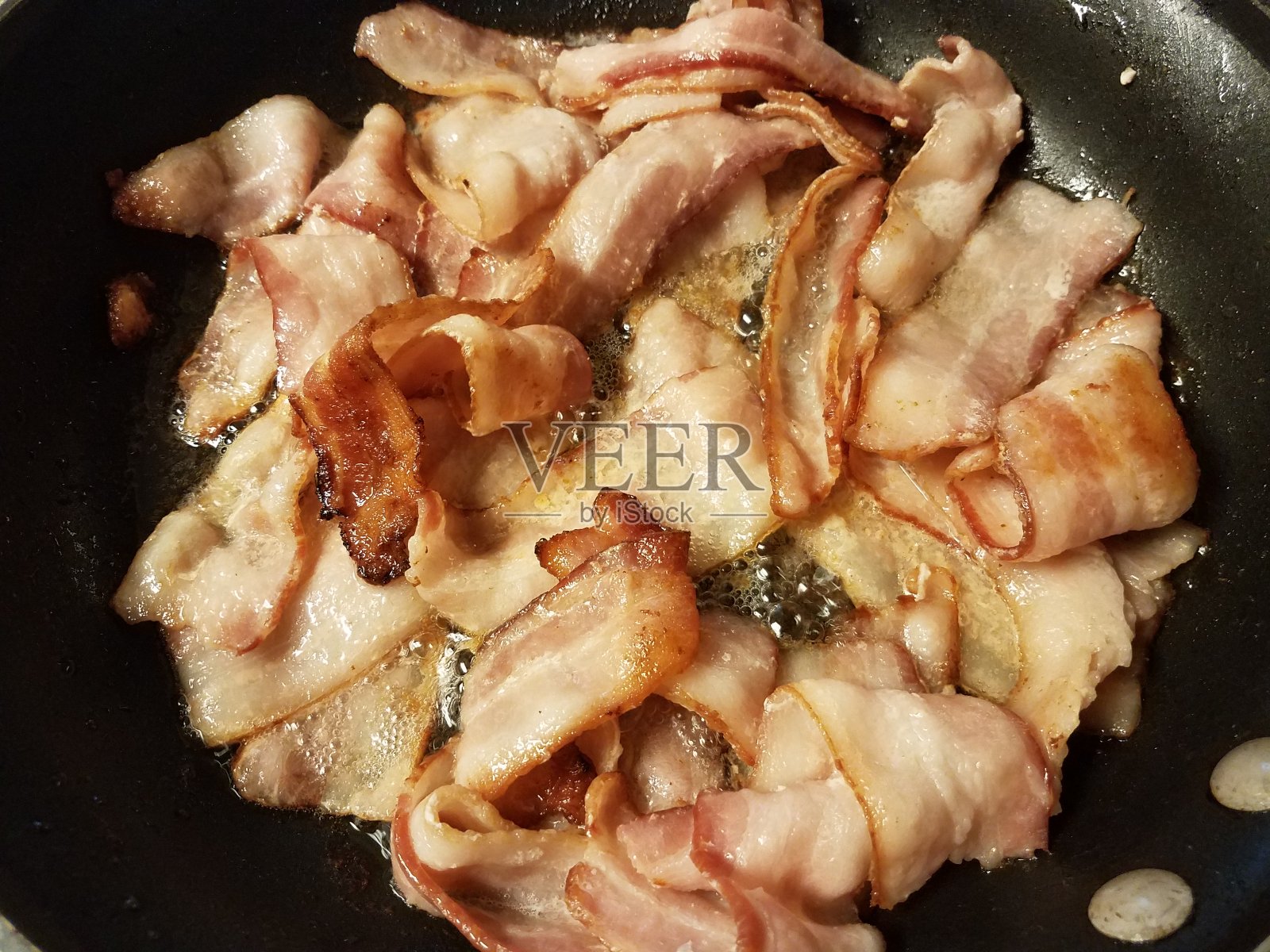 用煎锅或煎锅在炉子上煎培根照片摄影图片