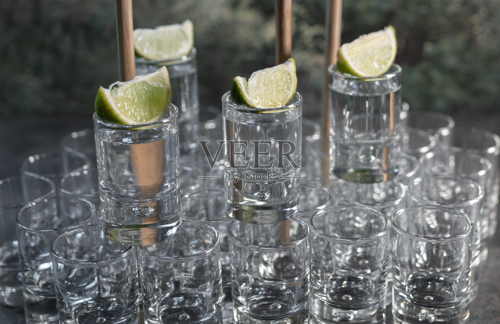 在一个黑色桌子上的酒吧里,龙舌兰杯上放柠檬片,其他杯子上也放柠檬片——豪华闪亮的杯子照片摄影图片