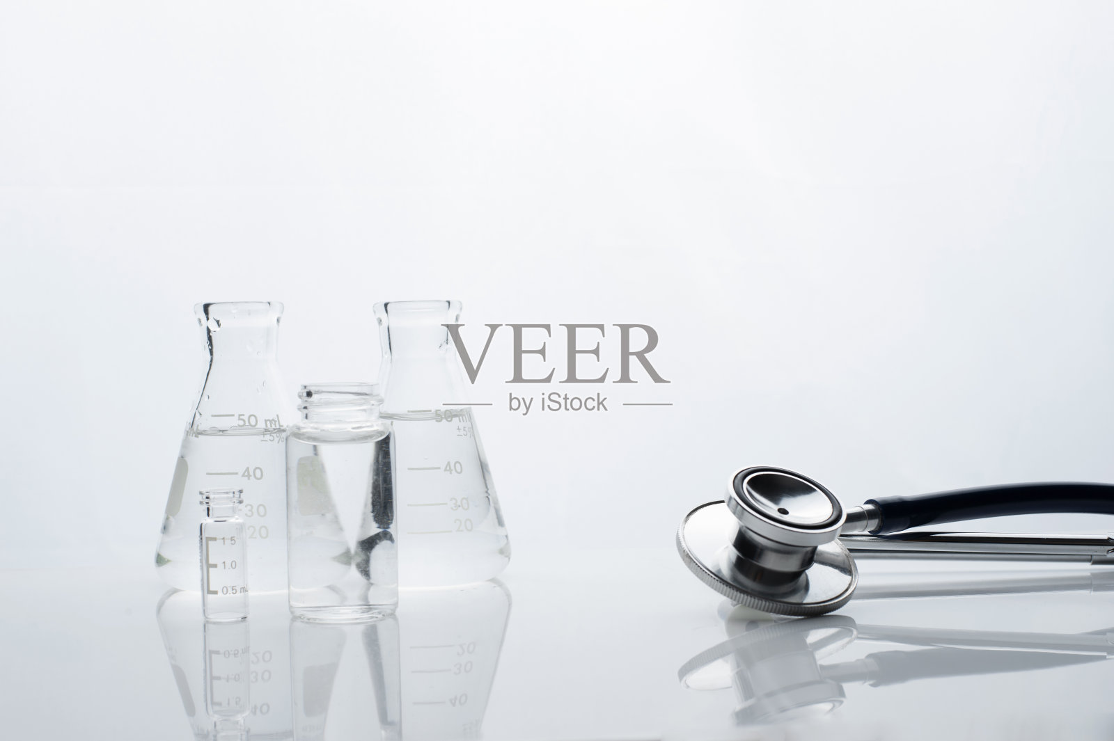 用于健康诊断的金属听诊器,配有白色实验室背景的科学玻璃烧瓶和小瓶照片摄影图片