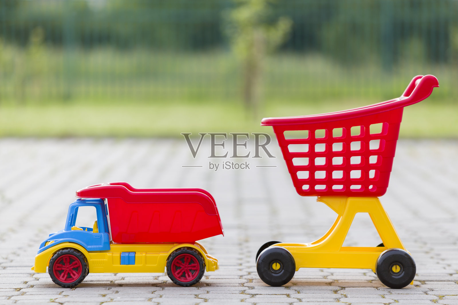 在阳光明媚的夏日,孩子们在户外玩的五颜六色的塑料玩具。汽车卡车和购物手推车。照片摄影图片