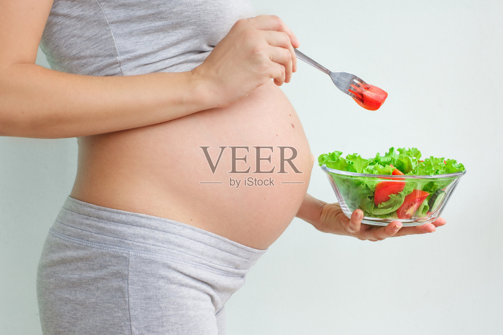 健康的营养和怀孕。孕妇的肚子和蔬菜沙拉。孕期营养。素食主义和怀孕。孕期维生素,孕期饮食照片摄影图片