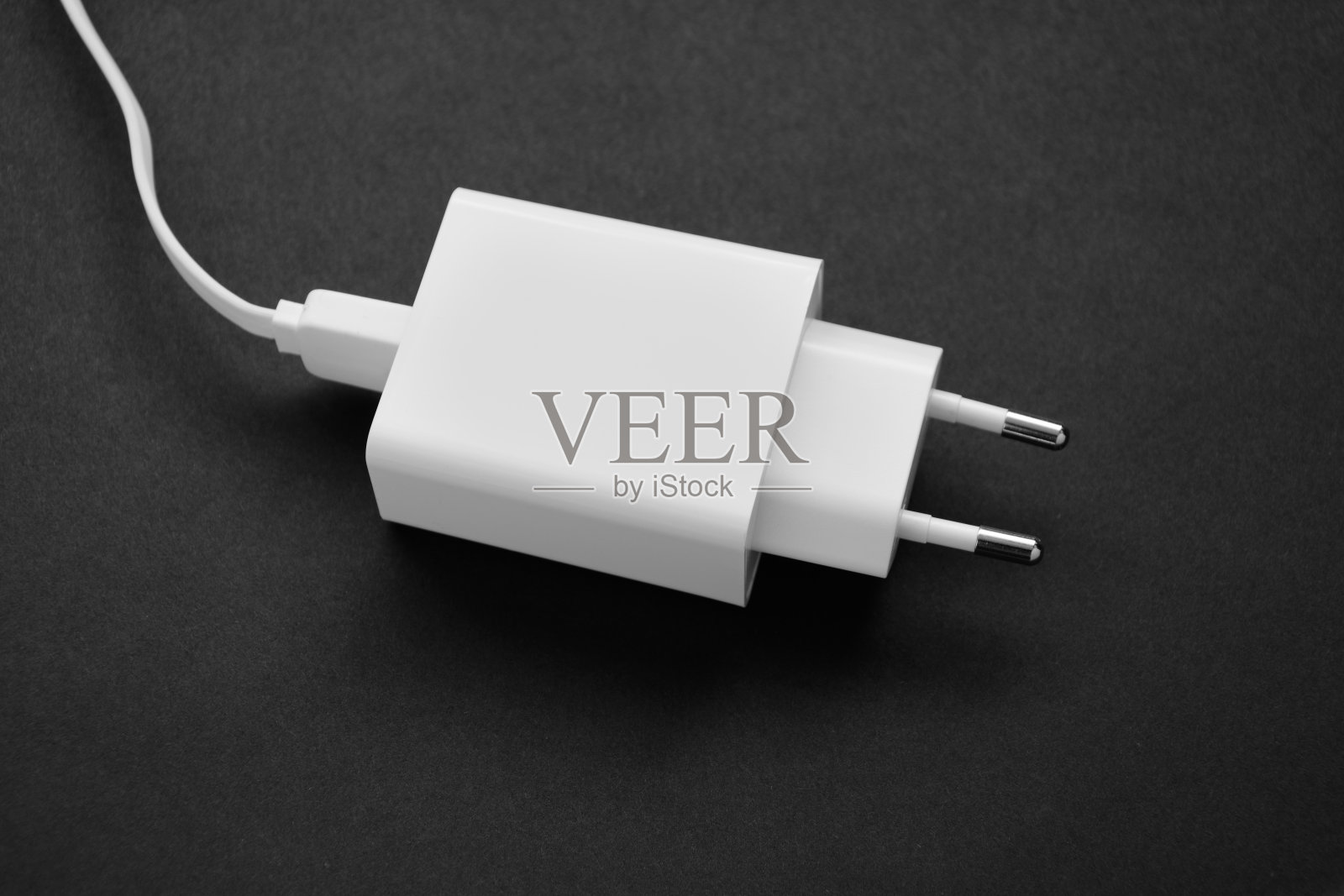 黑色背景下智能手机的白色充电器照片摄影图片