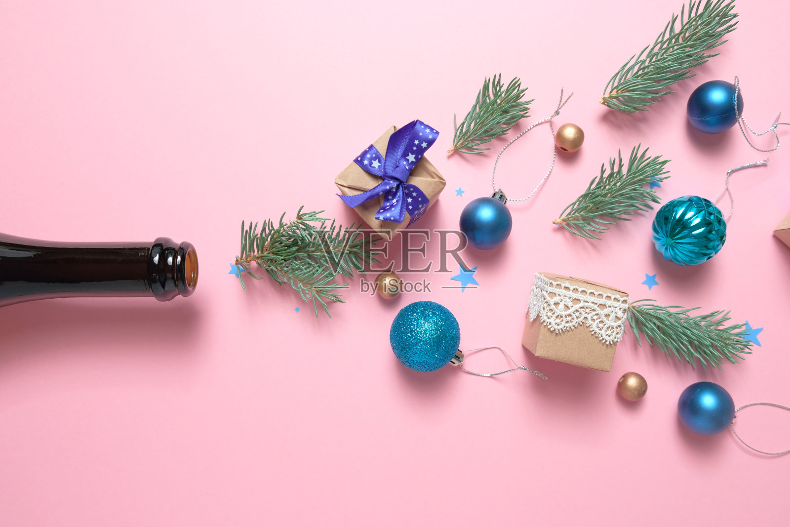 香槟瓶与不同的圣诞装饰在粉红色的背景。新年的概念。照片摄影图片