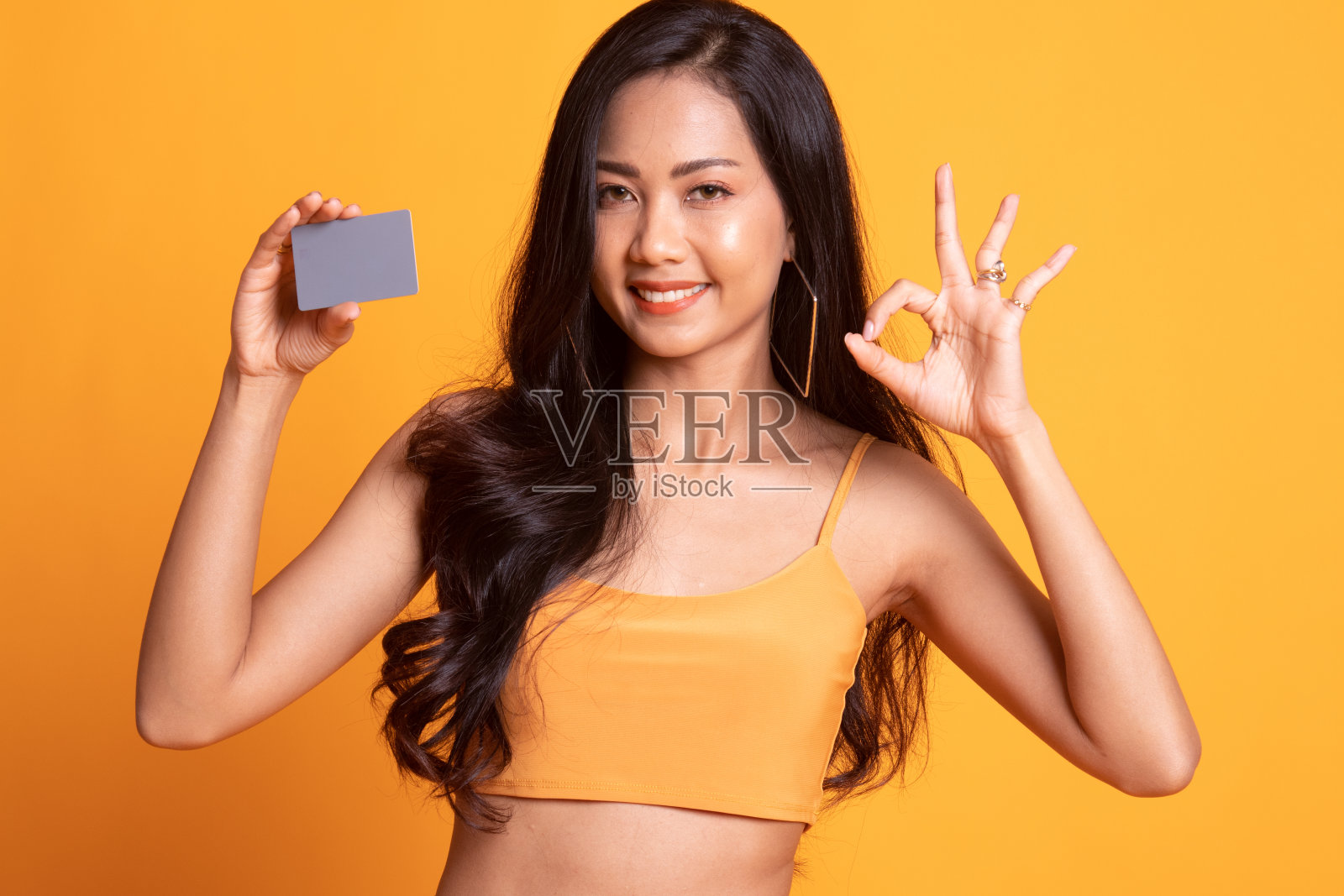 年轻的亚洲女子用一张空白卡片表示OK。照片摄影图片