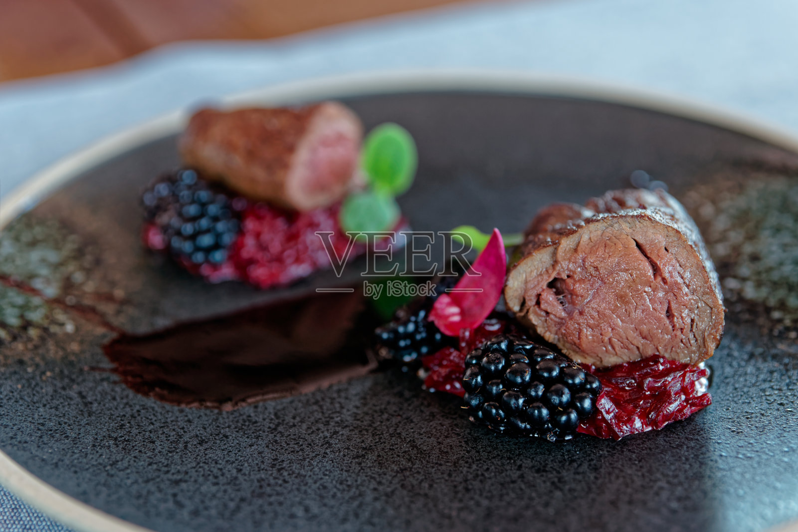 深色盘子上的鹿肉,特写照片摄影图片