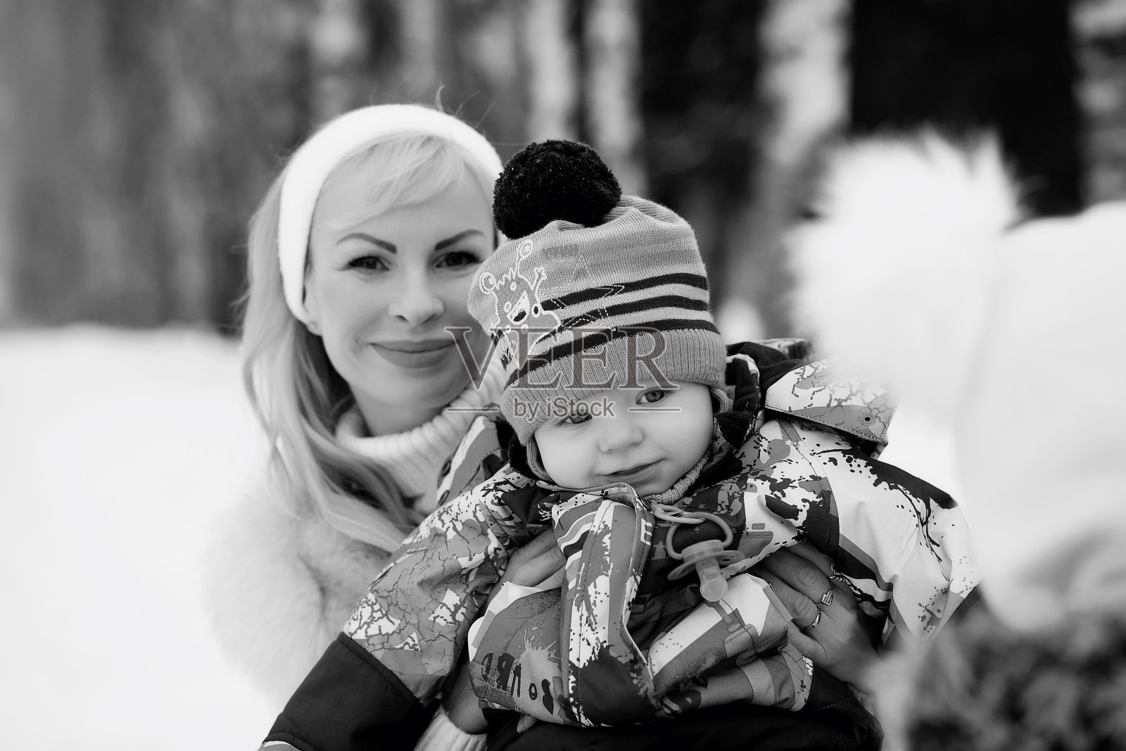 年轻母亲在冬日抱着婴儿散步。照片摄影图片