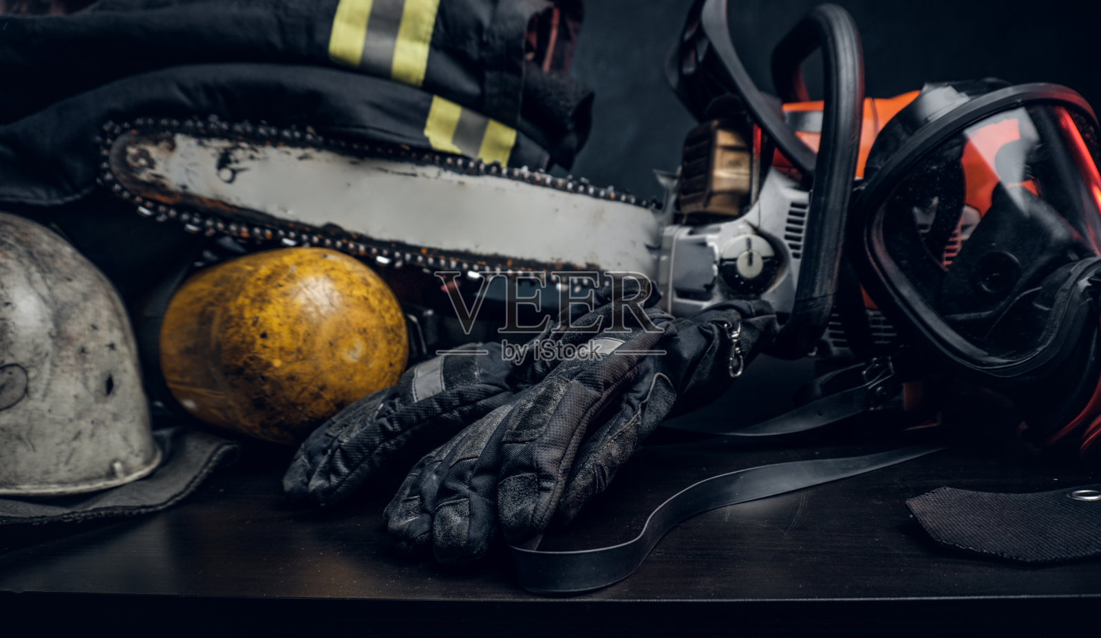 安全制服放在桌子上,配有呼吸器和电锯。照片摄影图片