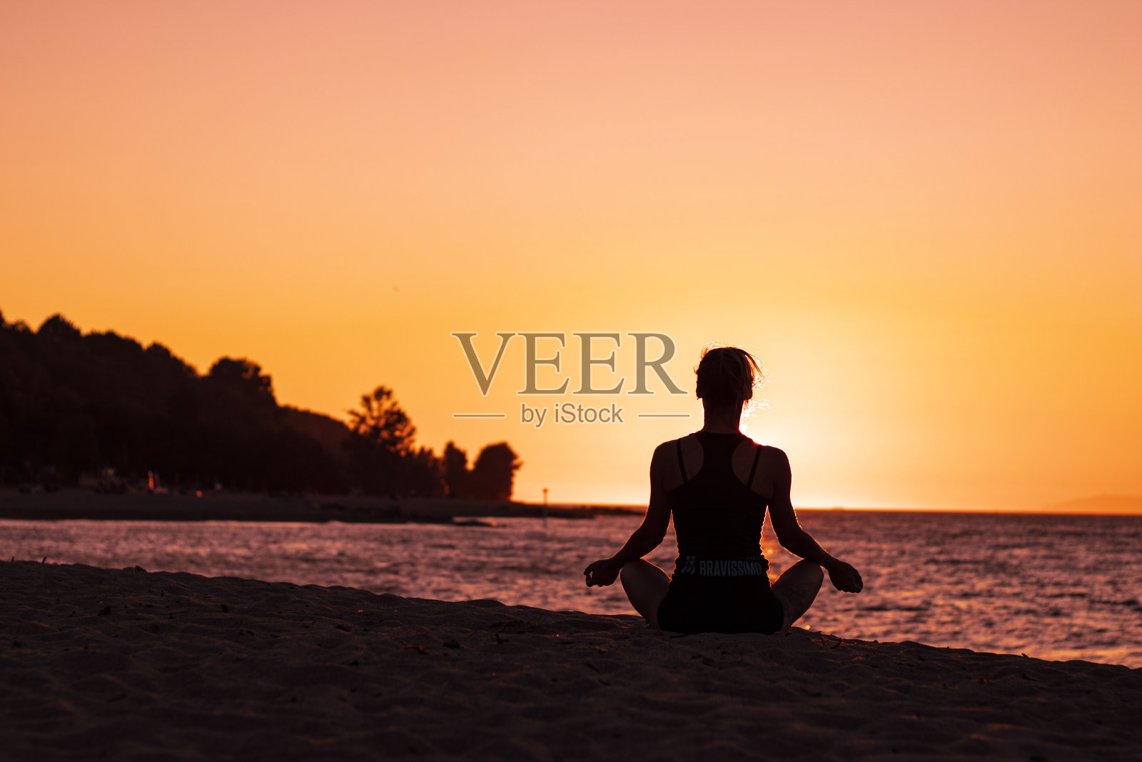 女子瑜伽冥想在沙滩上的日落莲花姿势照片摄影图片