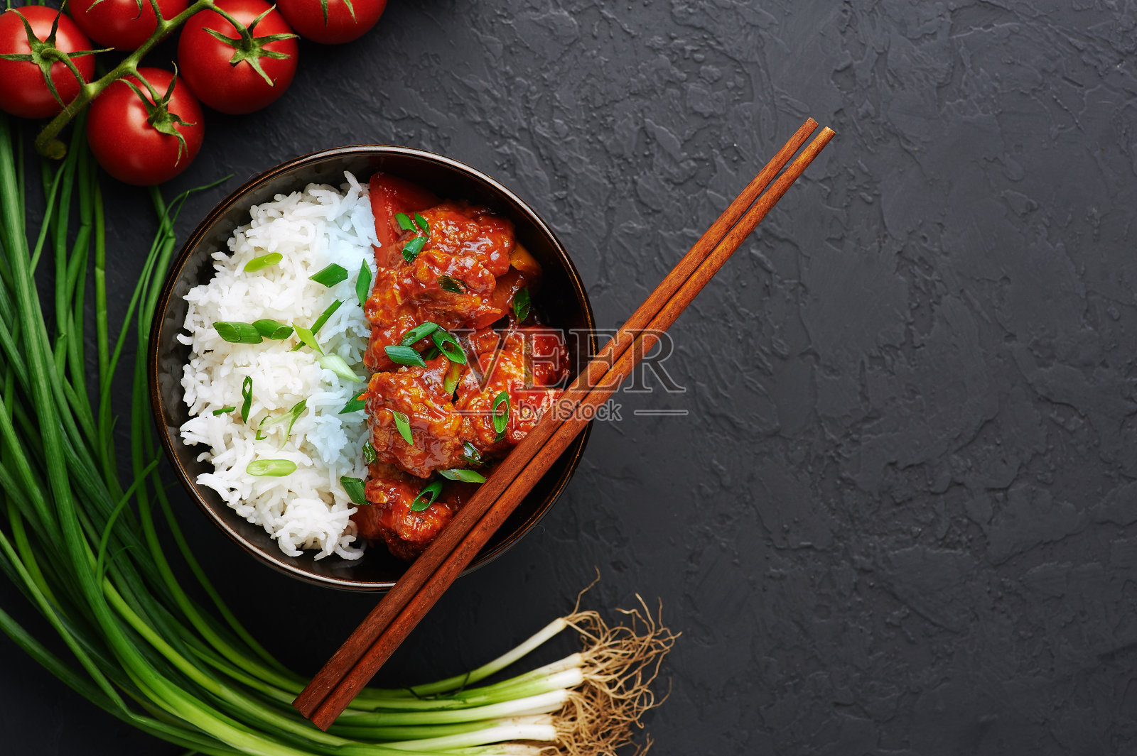 在黑色混凝土背景下,碗里的满洲鸡和印度香米。满族鸡是印度的中国菜,配以鸡胸肉、甜椒、番茄、酱油。本空间照片摄影图片