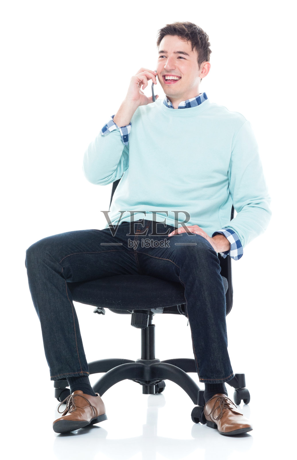 全长/一个20-29岁的成年人英俊的人/苗条/高个的白人男性/年轻男子坐在/休息在白色背景下穿着商务休闲/毛衣/牛仔裤谁是交谈/微笑/快乐/愉快照片摄影图片