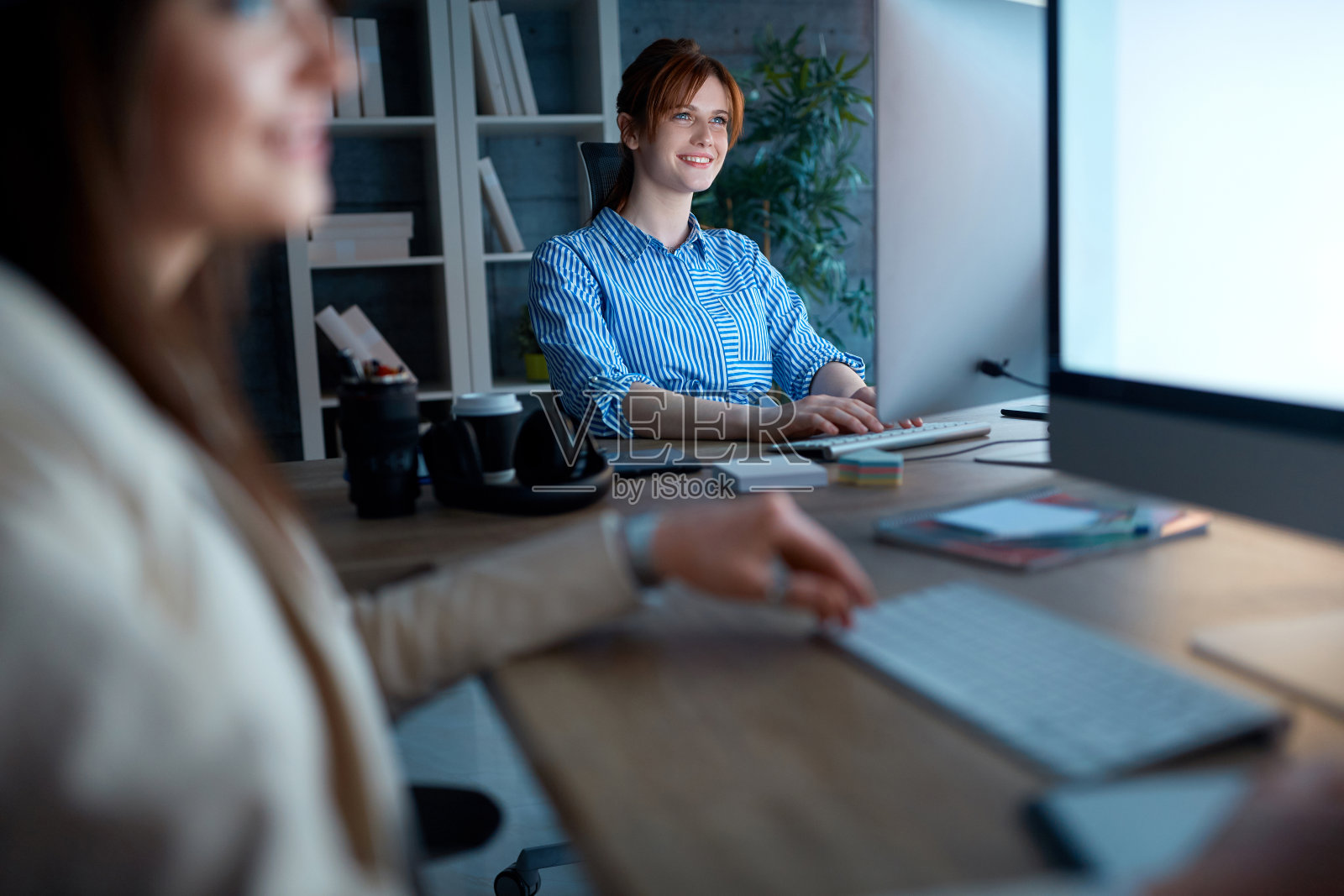 微笑着的商业女性在办公室里讨论加班工作的项目设计师照片摄影图片