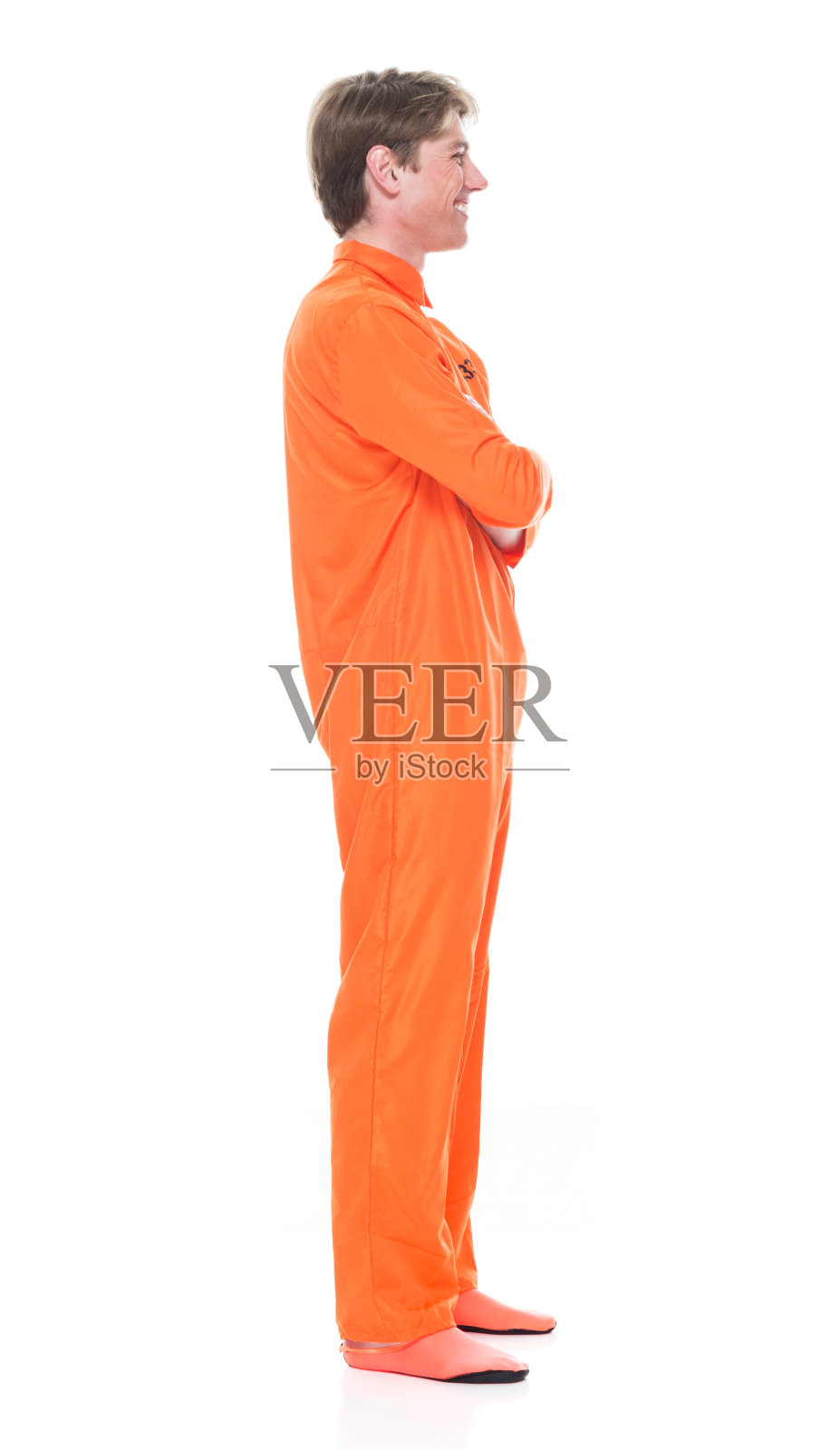 侧视图/全身/一个20-29岁的成年人英俊的人白种年轻男子/男性在白色背景下穿着连身衣/制服谁是自信/微笑/快乐/双臂交叉的愉快/犯罪照片摄影图片