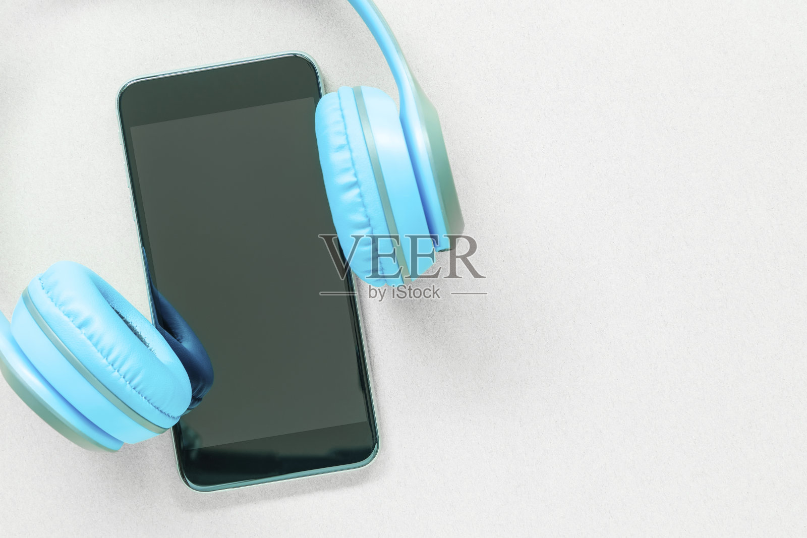 白色桌子上放着带耳机的手机或智能手机,有空闲空间。用音乐理念放松。照片摄影图片