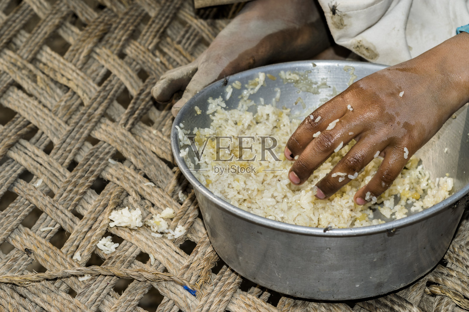 一个饥饿的孩子正在一个由慈善组织组织的难民营里吃饭照片摄影图片