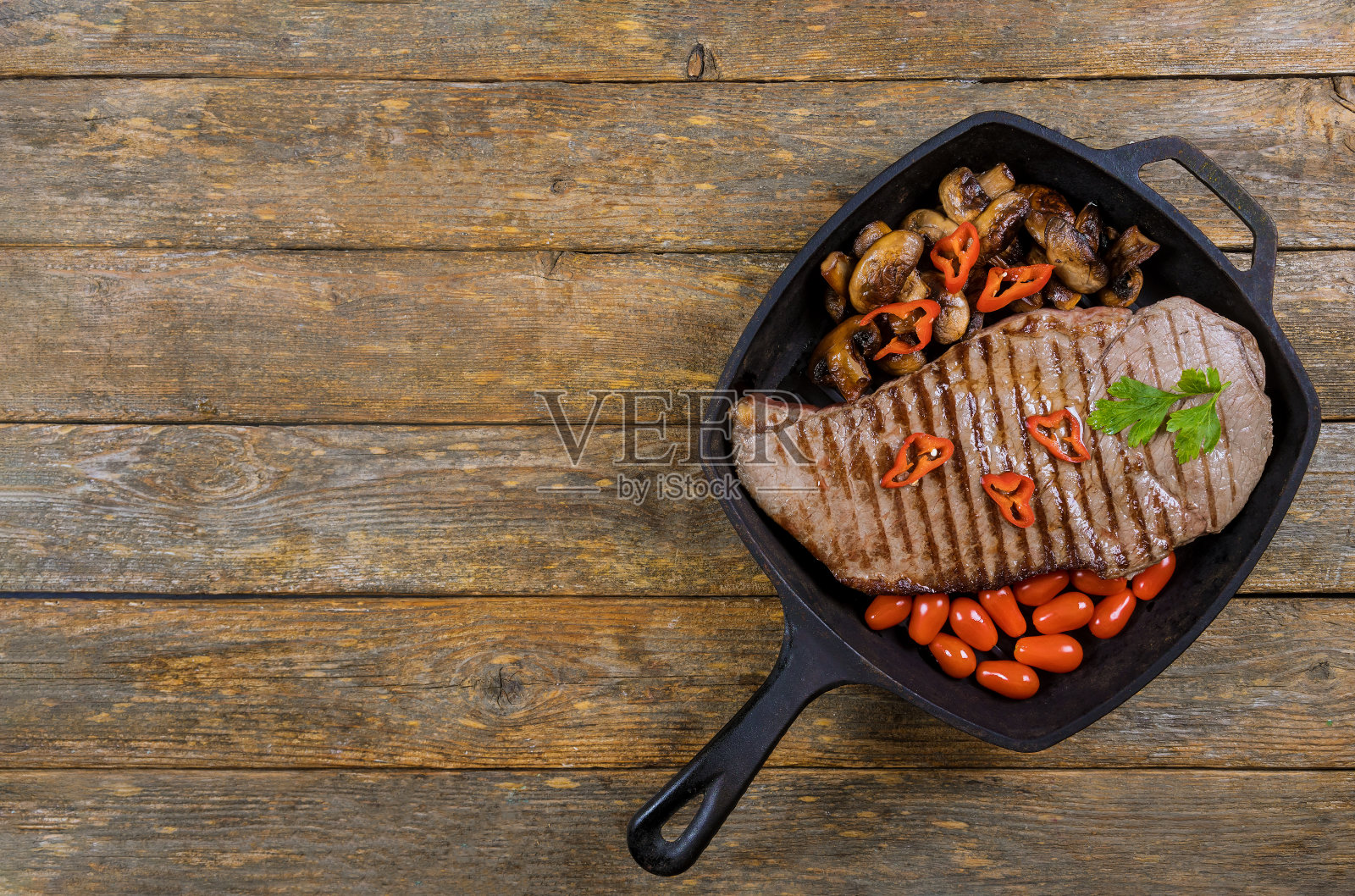 烤盘里的牛排配烤蘑菇。照片摄影图片