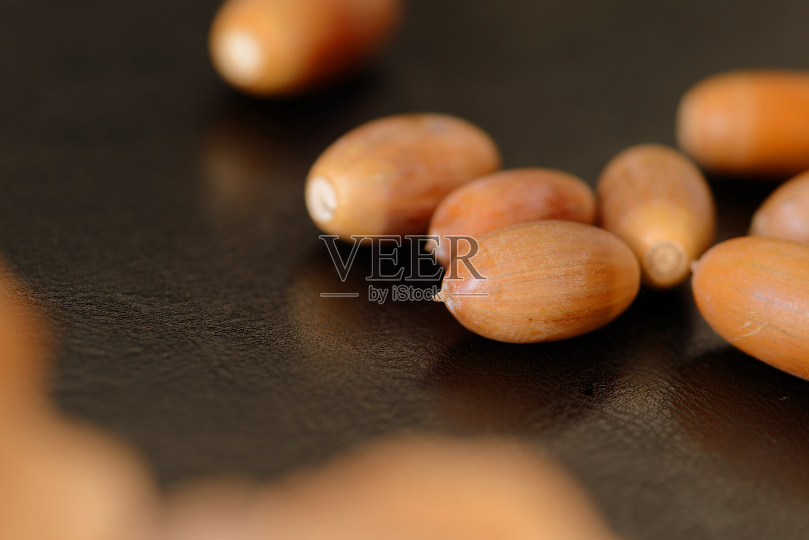 橡子和干燥的橡树叶在黑暗的表面近距离。秋天背景照片摄影图片