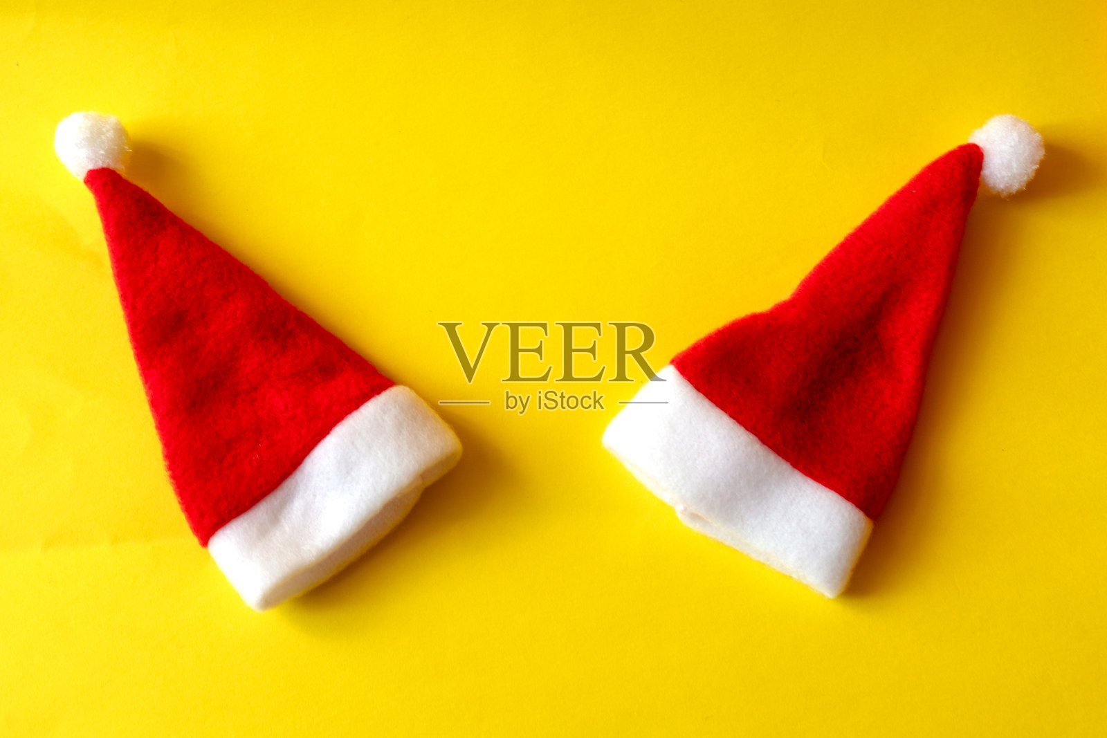 两顶黄色背景上的红色圣诞老人帽。夫妇在爱。爱的概念和新年和圣诞节照片摄影图片