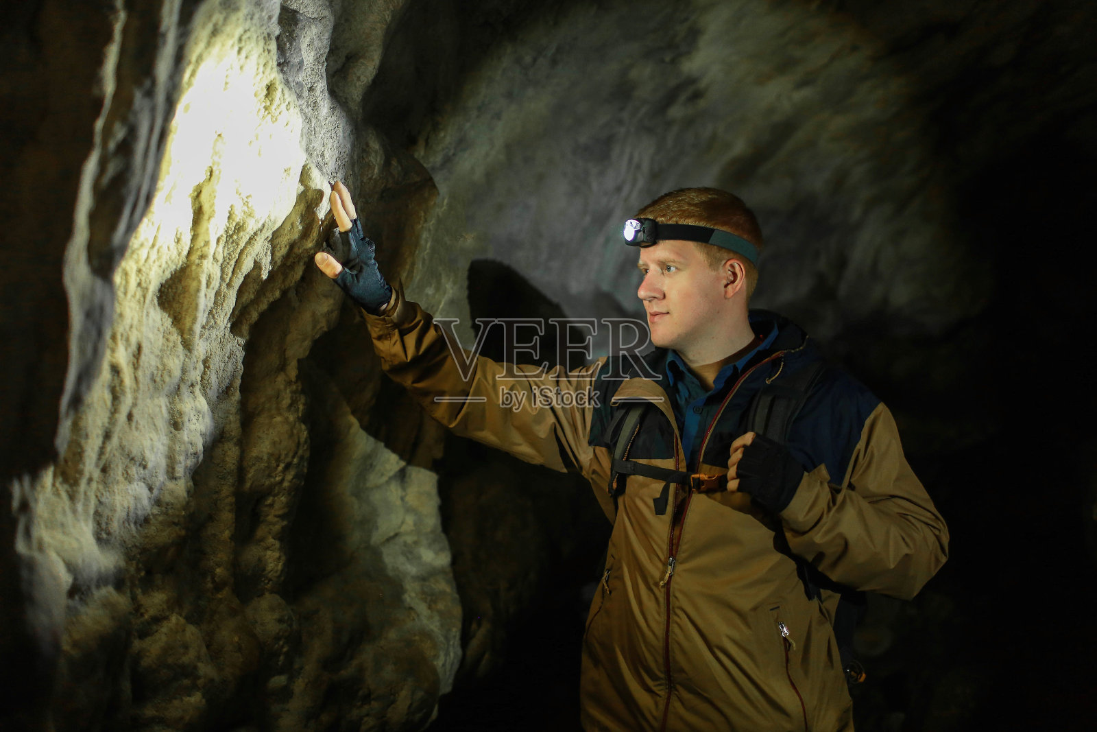 在喀斯特洞穴里,人们触摸着一堵墙照片摄影图片