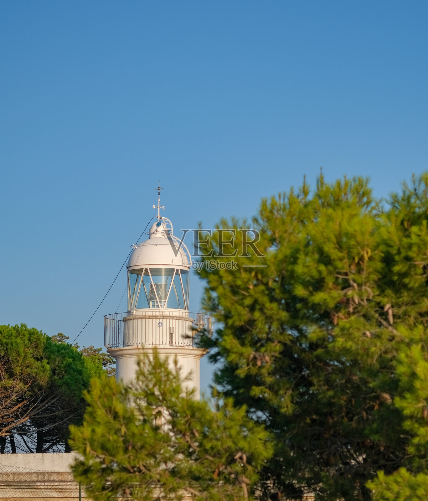 灯塔周围的树木在蓝天背景。照片摄影图片