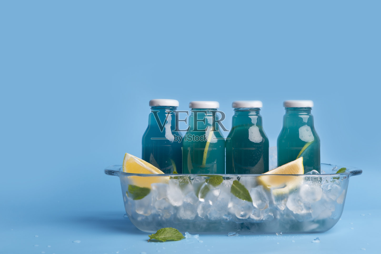 蓝色瓶装夏日清凉饮品,配新鲜柠檬片照片摄影图片