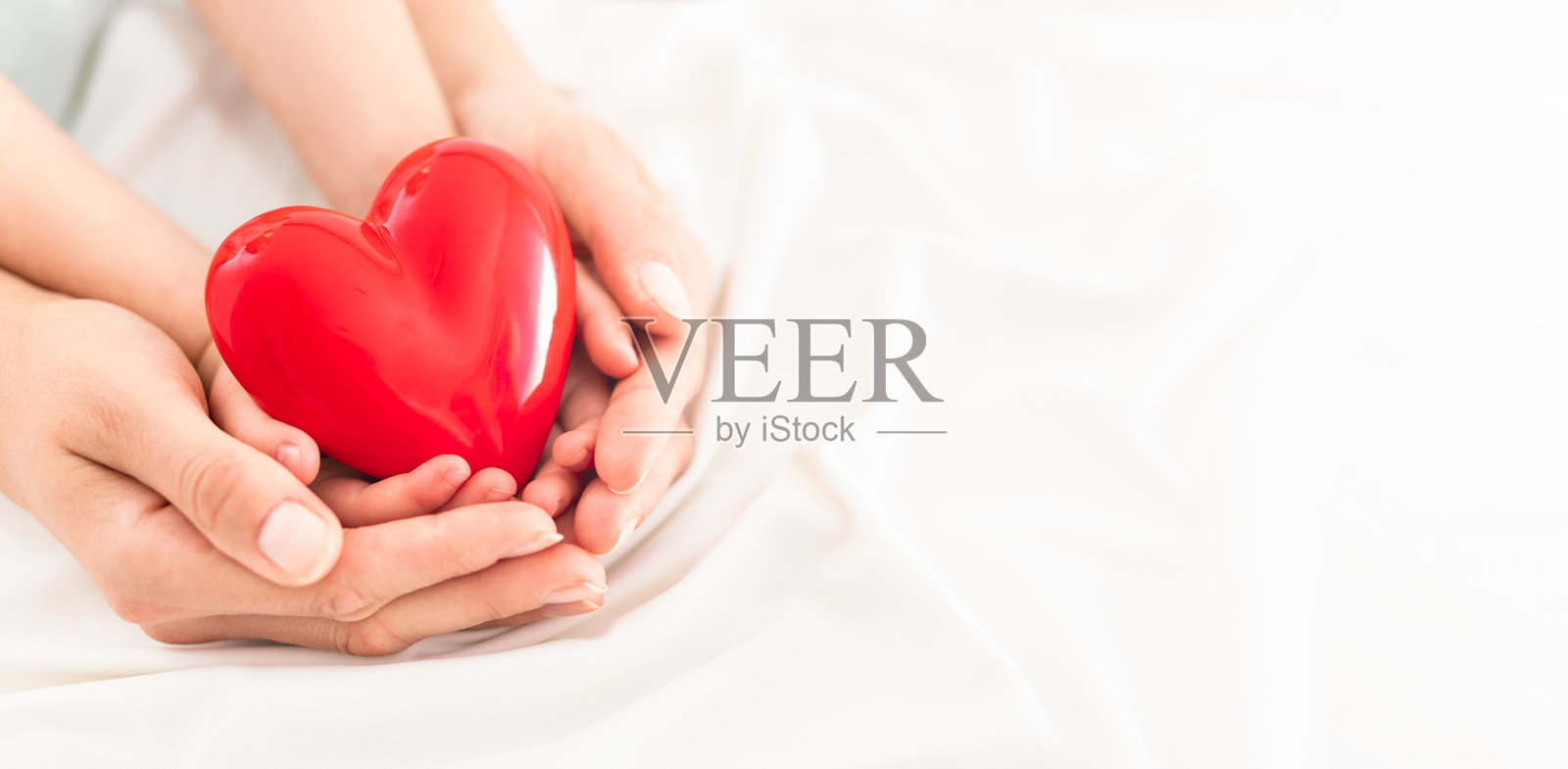 大人和小孩抱着红心。照片摄影图片