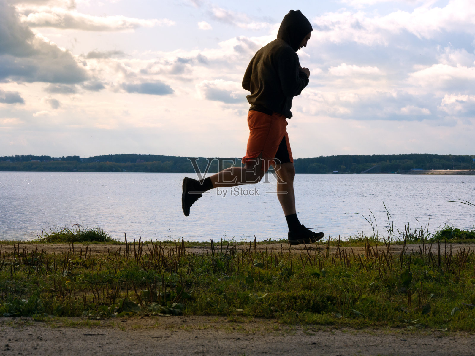 日落时分在河边慢跑的男子照片摄影图片