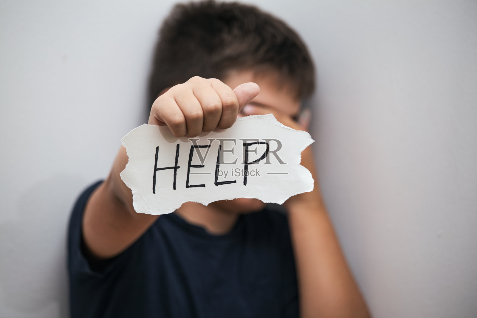 孤独少年抑郁地坐着,举着写有求助信息的纸照片摄影图片