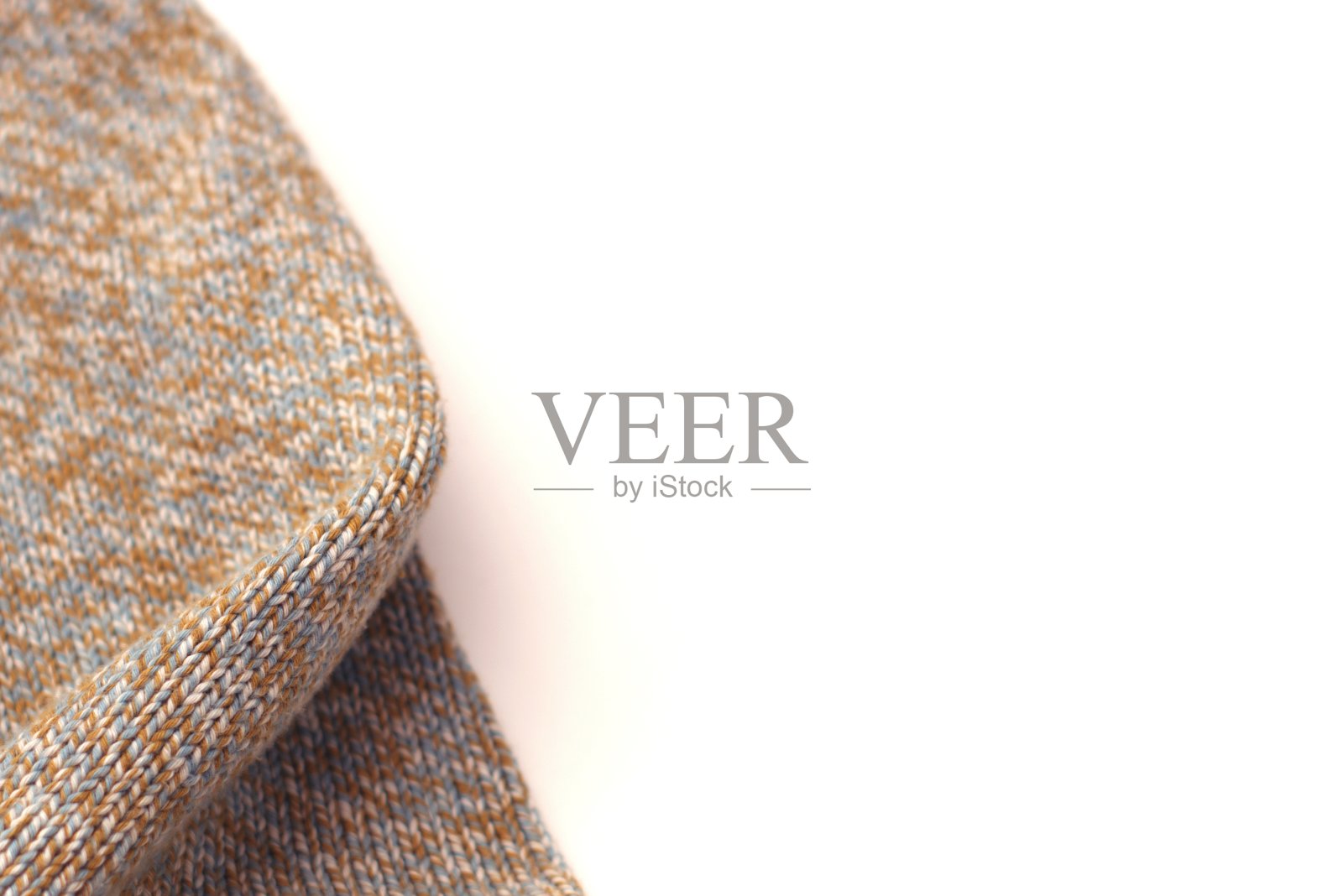 斑驳的米色针织毛衣在白色的背景。纹理细节特写。照片摄影图片