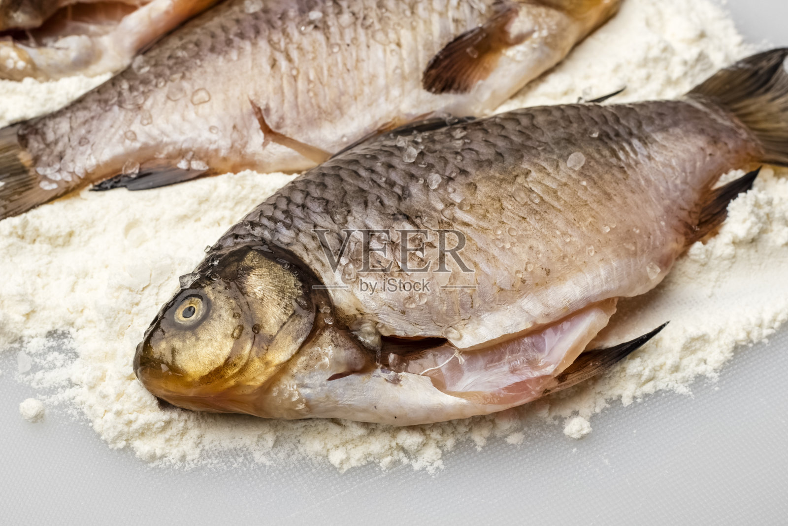 新鲜的鲫鱼,面粉中加入粗盐,放在白色砧板上。烹饪,关闭照片摄影图片