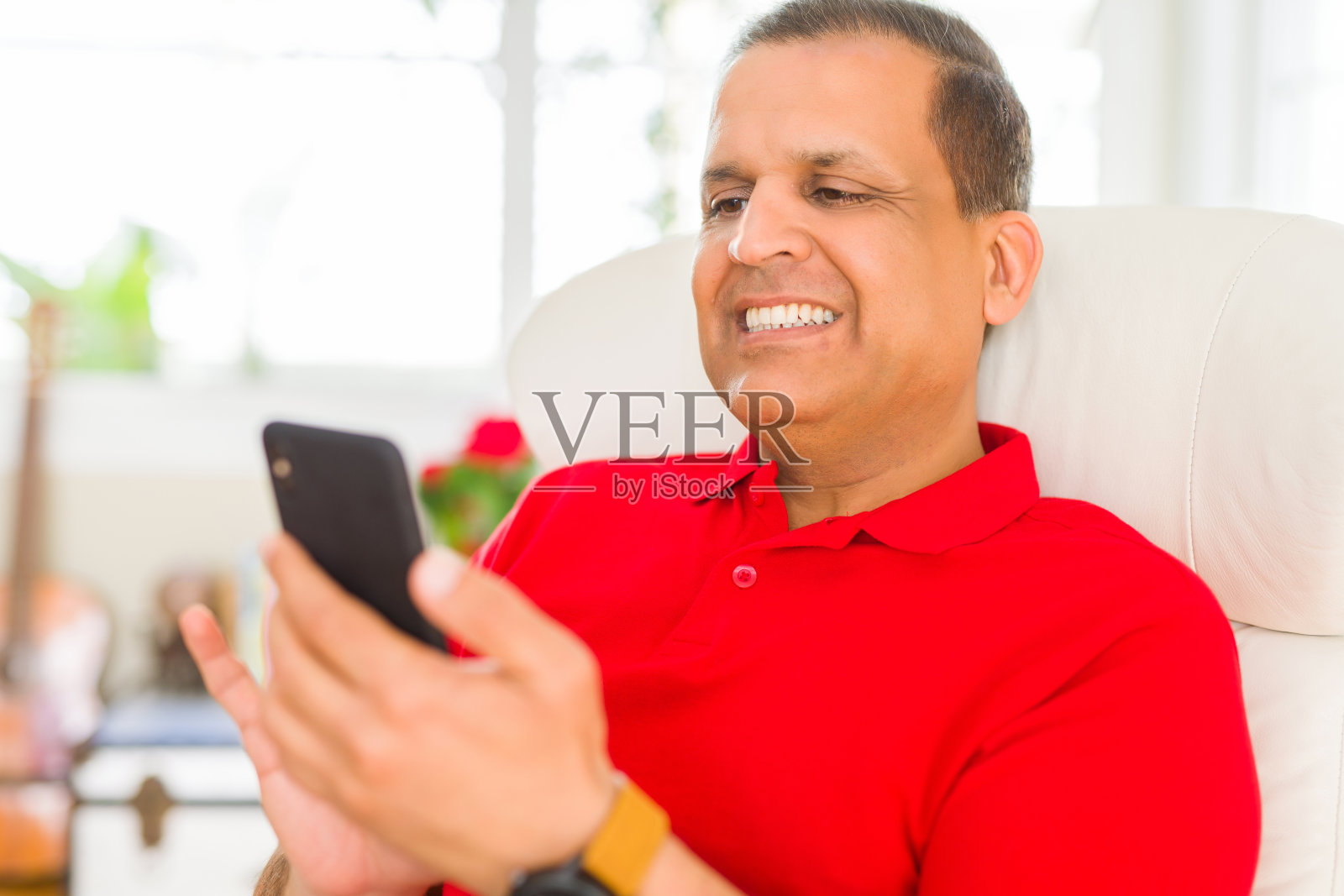 中年男子坐在家里的沙发上用智能手机微笑照片摄影图片