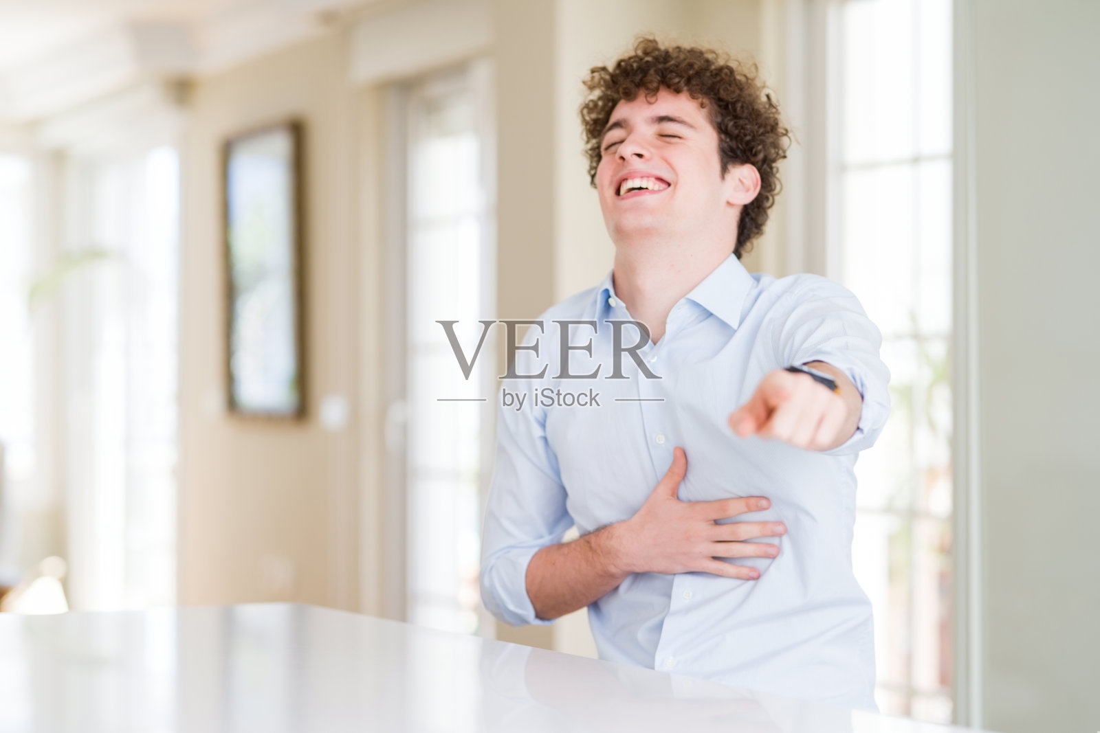 年轻的商人用卷发读头笑着你,用手指着镜头,露出羞愧的表情照片摄影图片