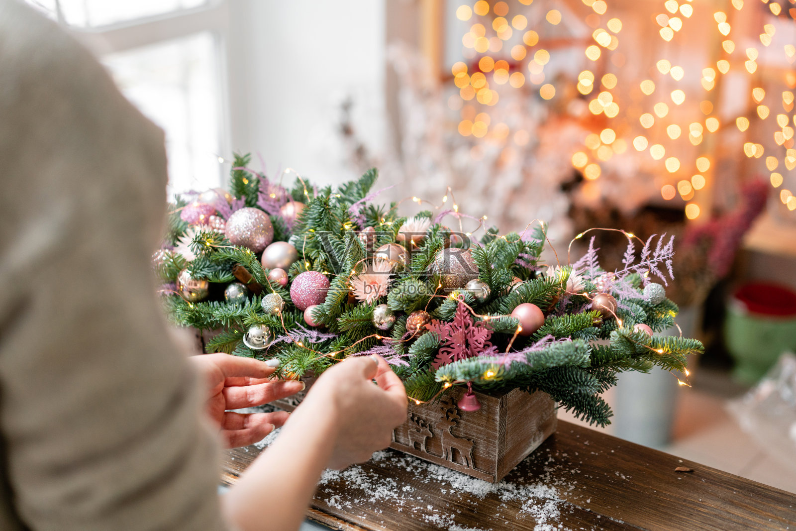 年轻女子创造和装饰美丽的节日安排新鲜云杉,装饰在一个乡村的木制盒子。圣诞节的心情。Garland bokeh背景。照片摄影图片