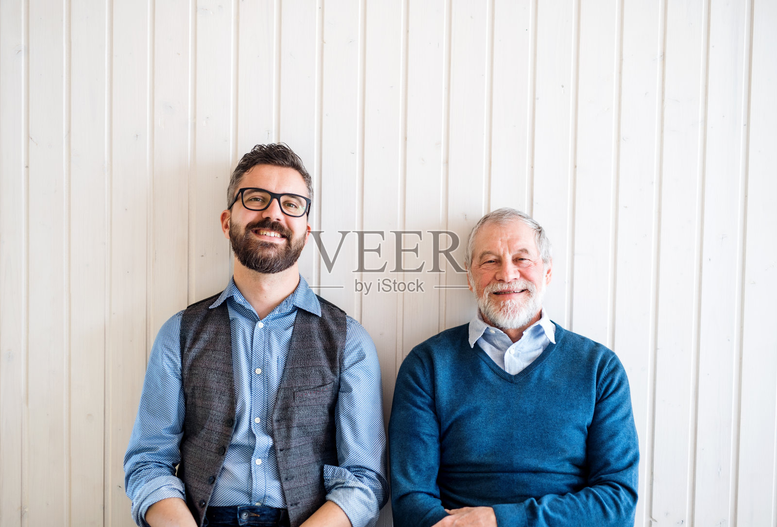 一幅成年潮人儿子和老父亲坐在家里地板上的肖像。照片摄影图片