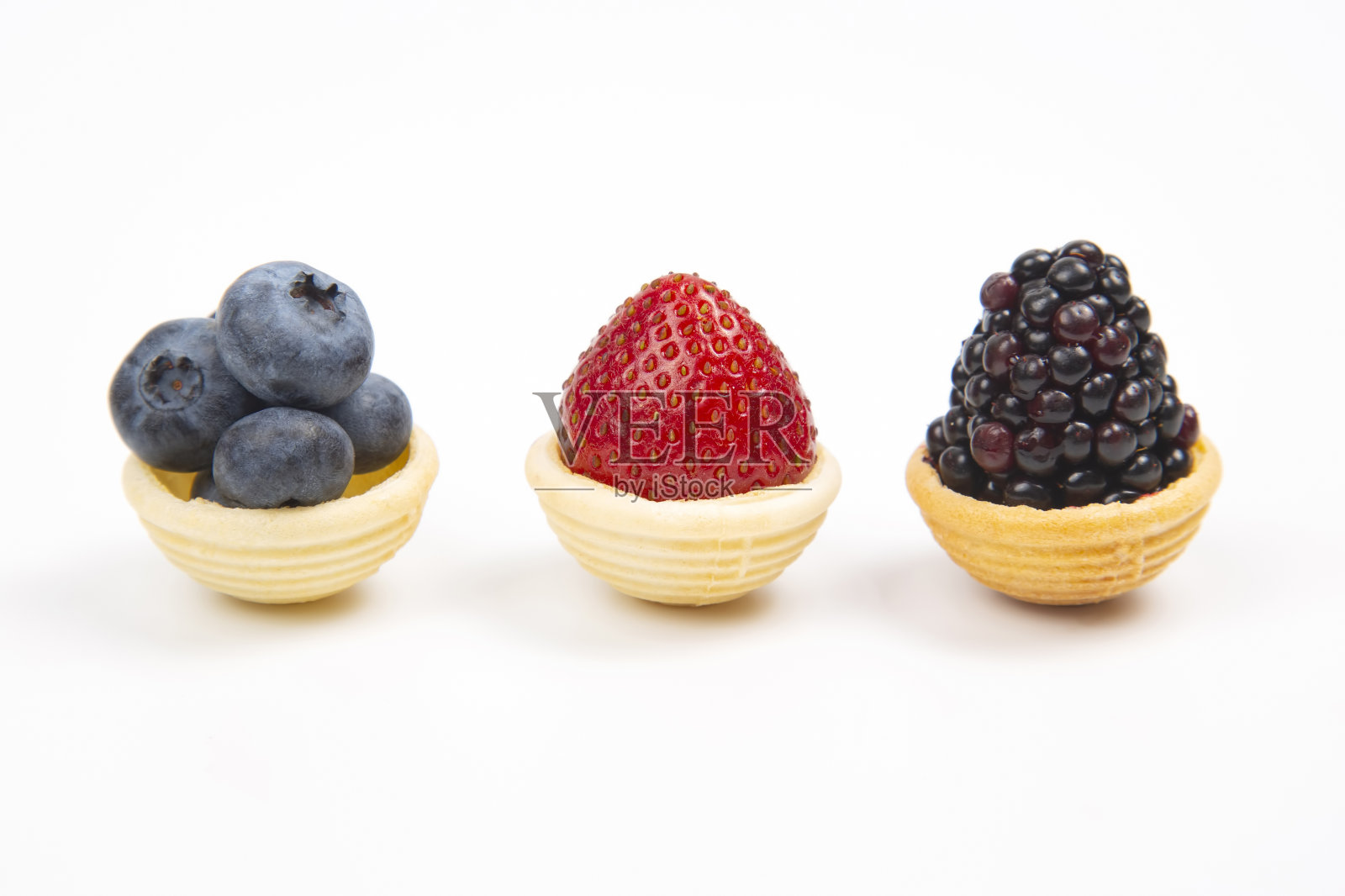 蓝莓,草莓和黑莓在华夫饼篮子在白色的背景照片摄影图片