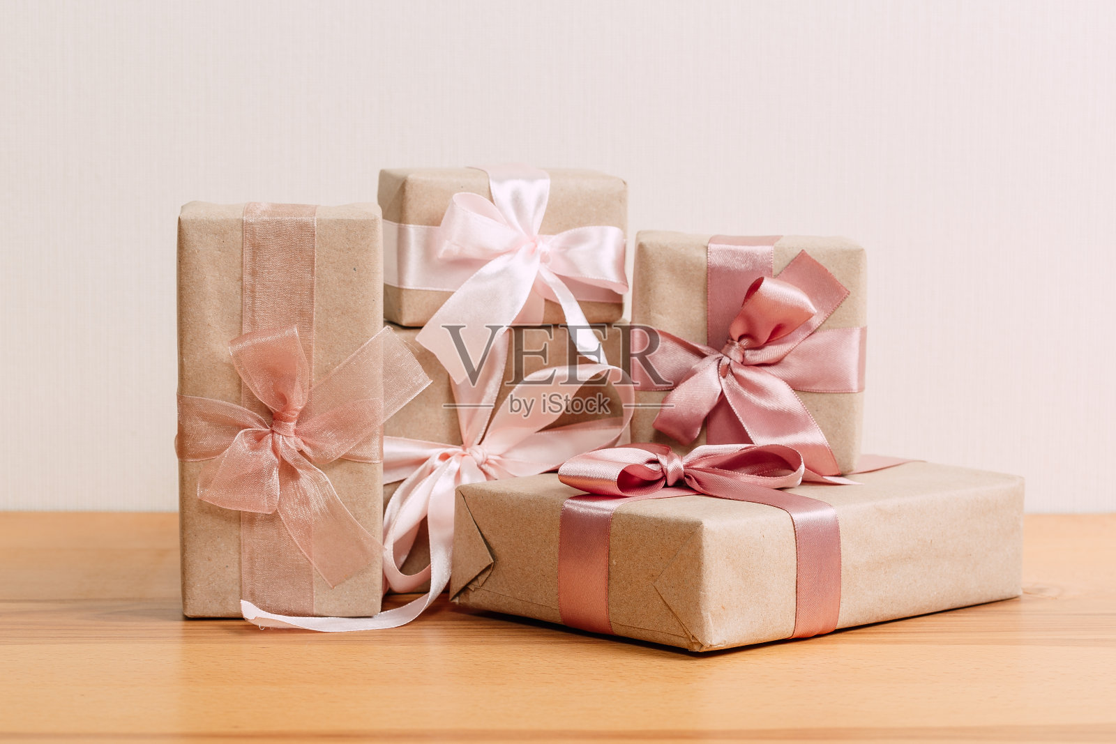 一套美丽的不同的礼品盒手工制作的粉红色蝴蝶结在木桌子上与灯光背景照片摄影图片
