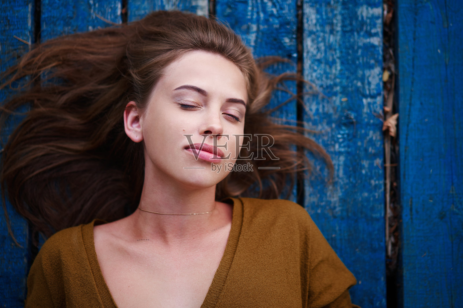美丽的白种年轻女子躺在木制的背景上。照片摄影图片