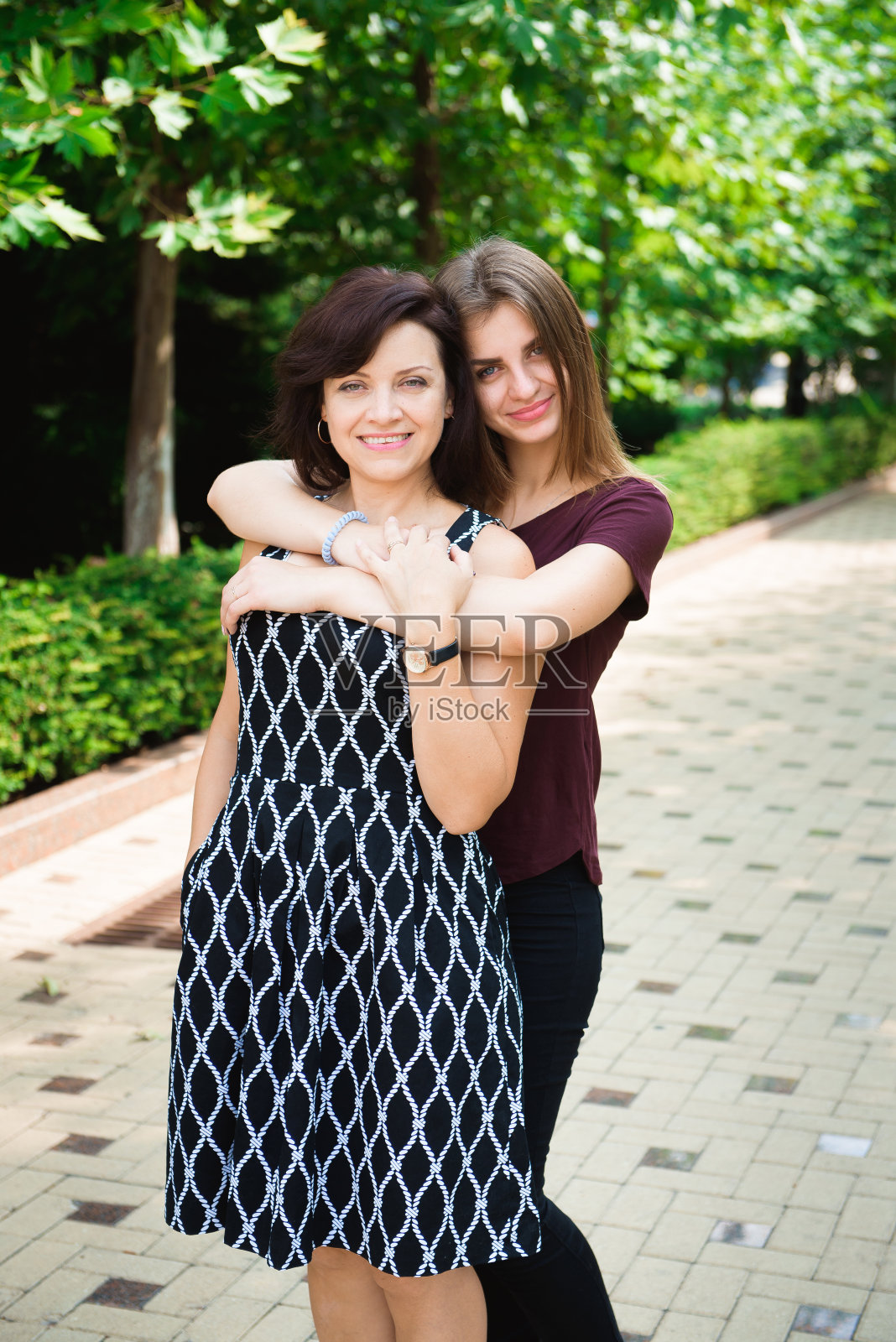 母亲和成年女儿一起在公园里。照片摄影图片