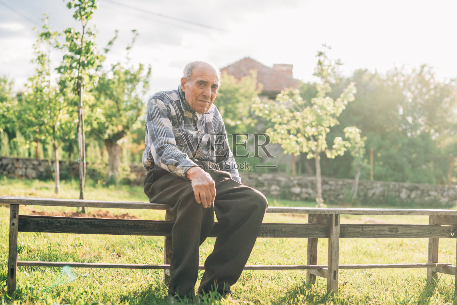 一位老人坐在户外的长椅上照片摄影图片