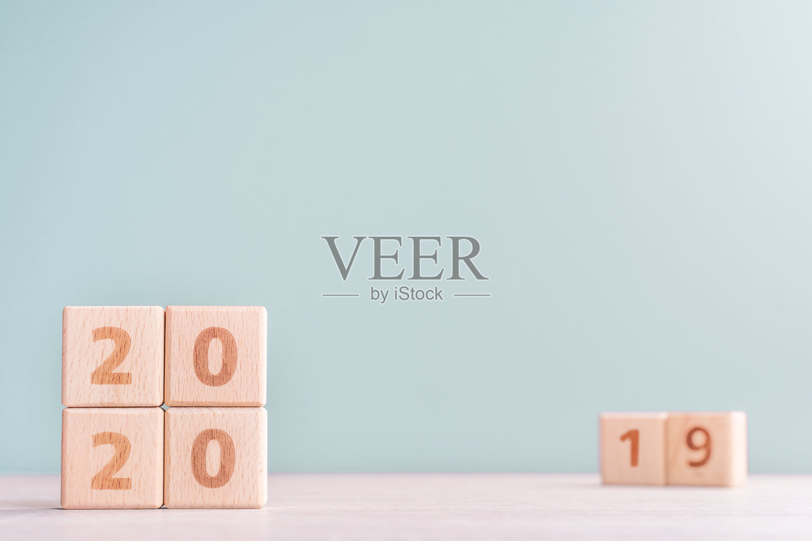 2020年和2019年新年倒计时设计理念——木桌上的木块立方体,低饱和度的绿色背景。照片摄影图片