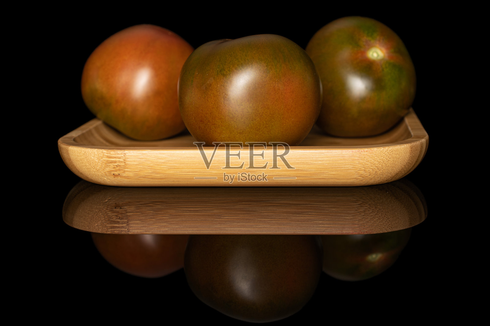 在黑色玻璃上分离的新鲜绿红番茄照片摄影图片